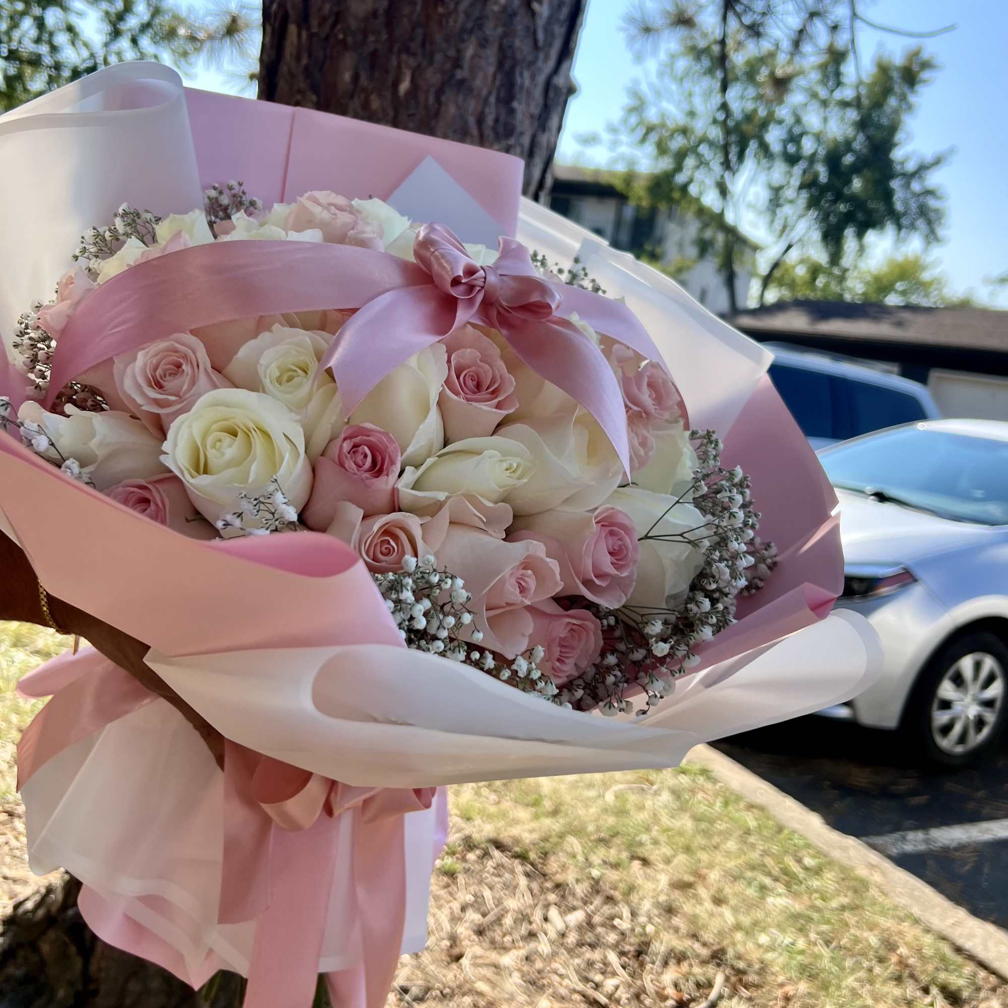 A lush bouquet featuring soft and delicate tones, wrapped in light pink