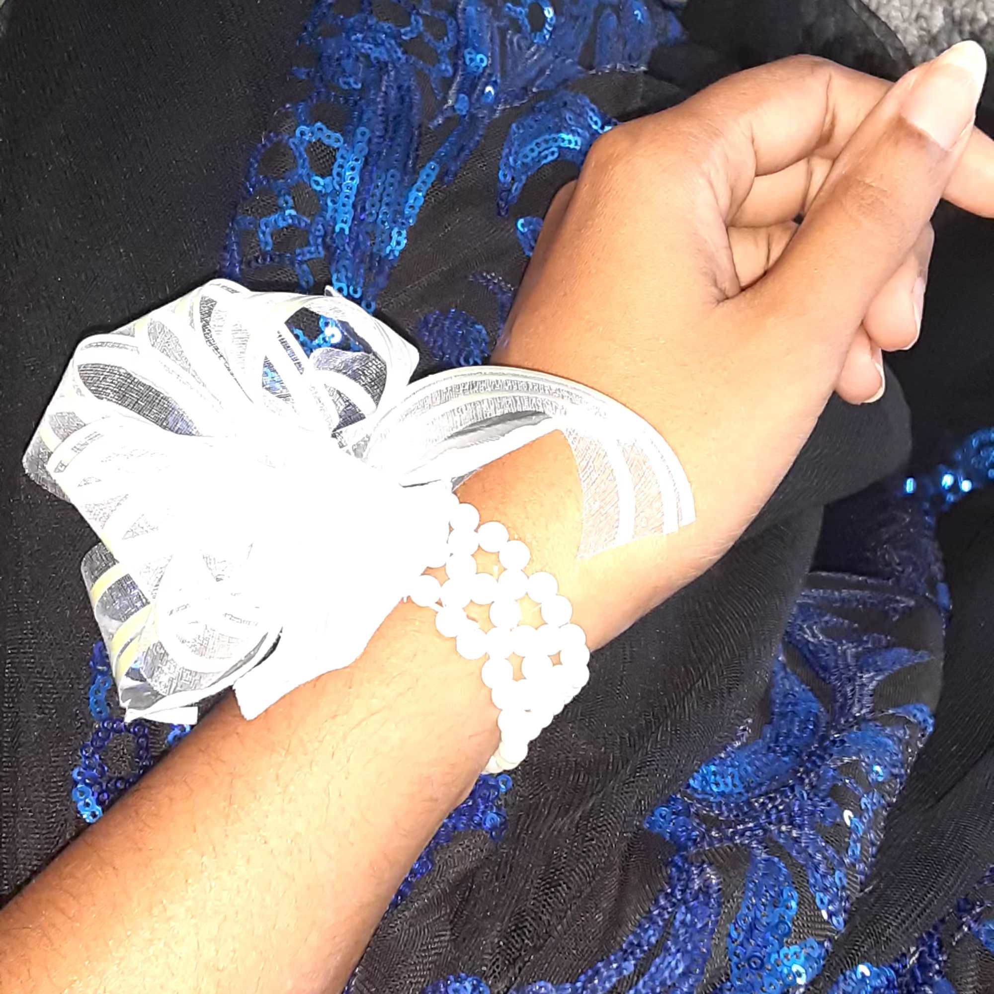 Iridescent pearl pull bow ribbon with silver base; secured on wrist by