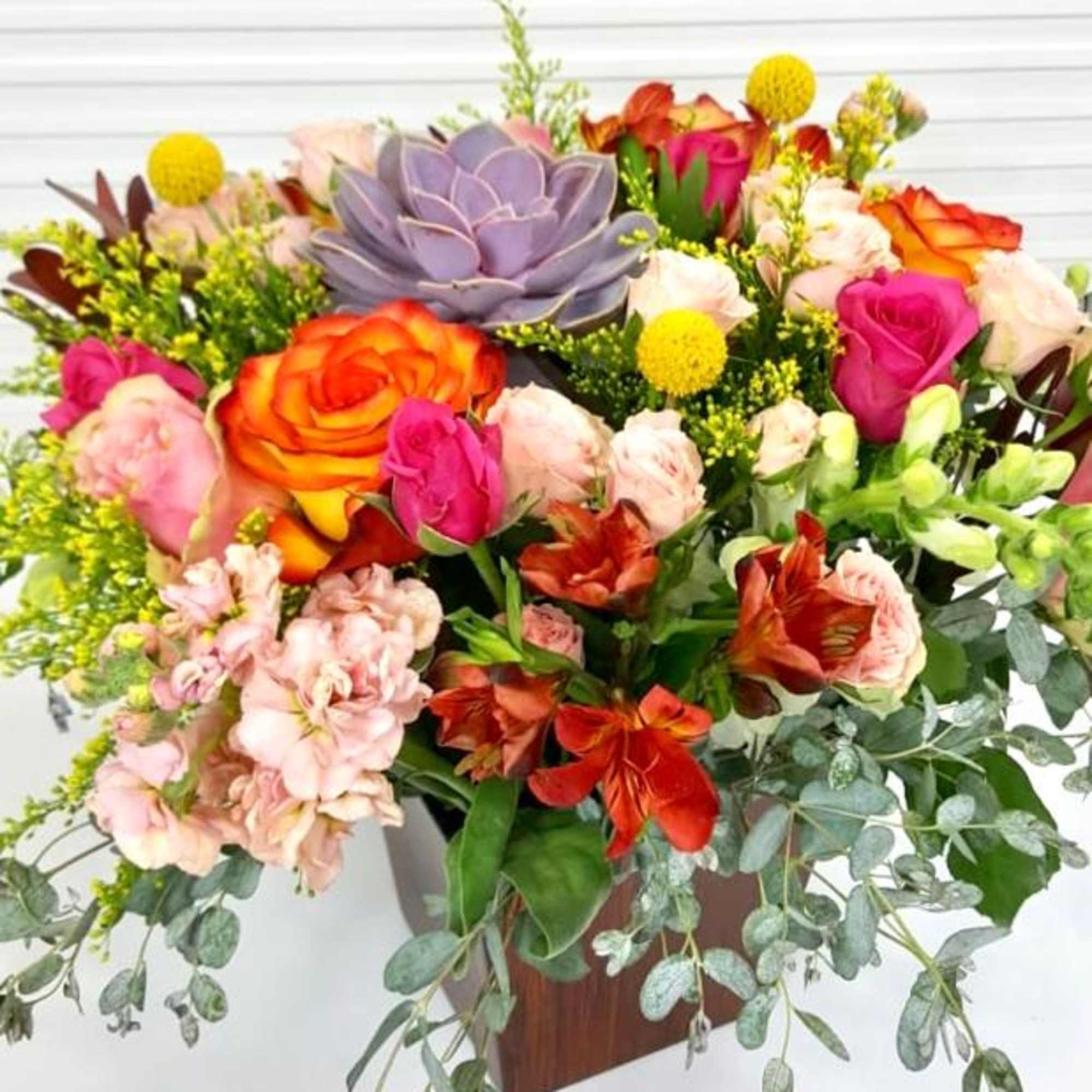 Centrally placed succulent surrounded by brightly colored selection of flowers including Roses