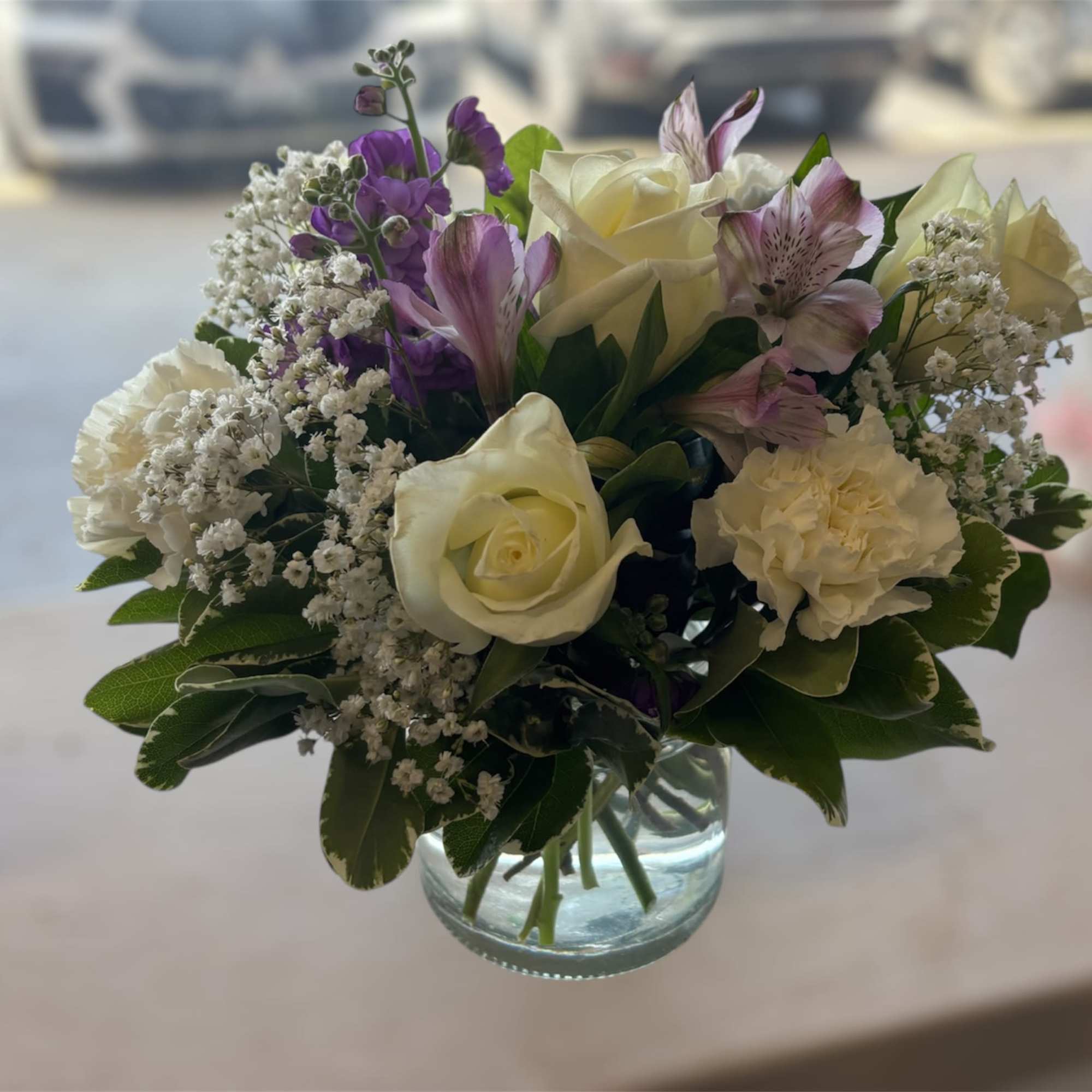 Arrangement with white roses and carnations; lavender alstroemerias and stock; accented with Arrangement with white roses and carnations; lavender alstroemerias and stock; accented with