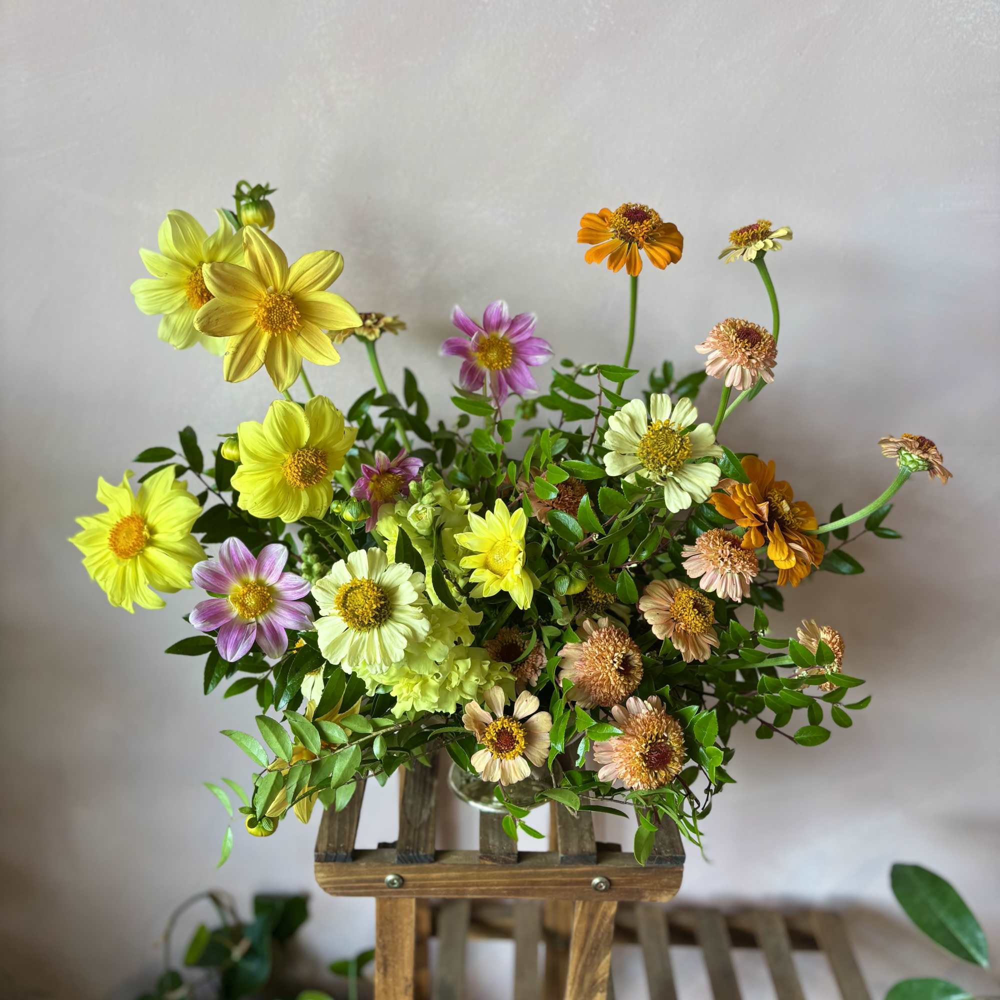 A happy mix of yellow, pink, and orange flowers with flowing greenery.