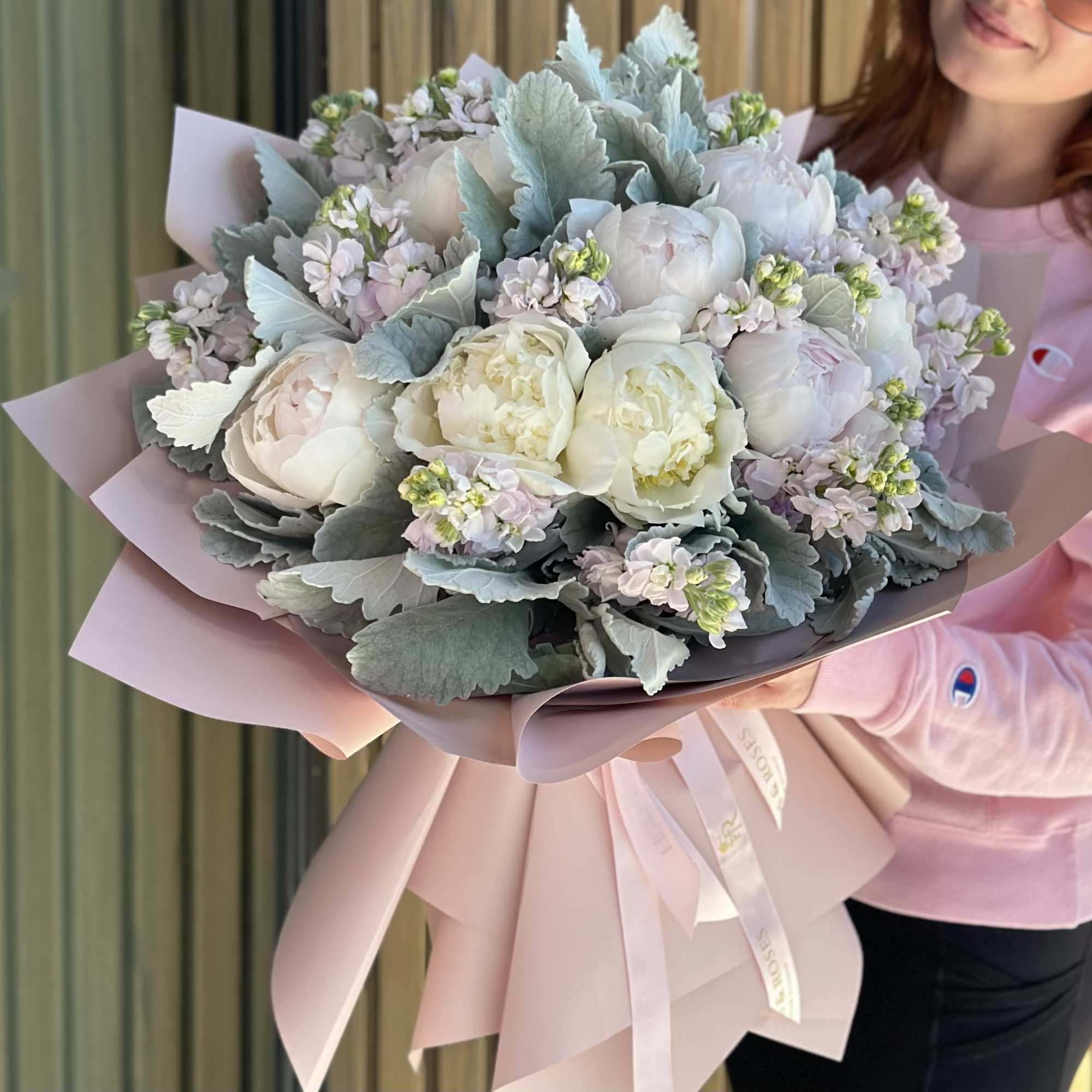 A hand-tied bouquet with pastel peonies features full, delicate blooms arranged in