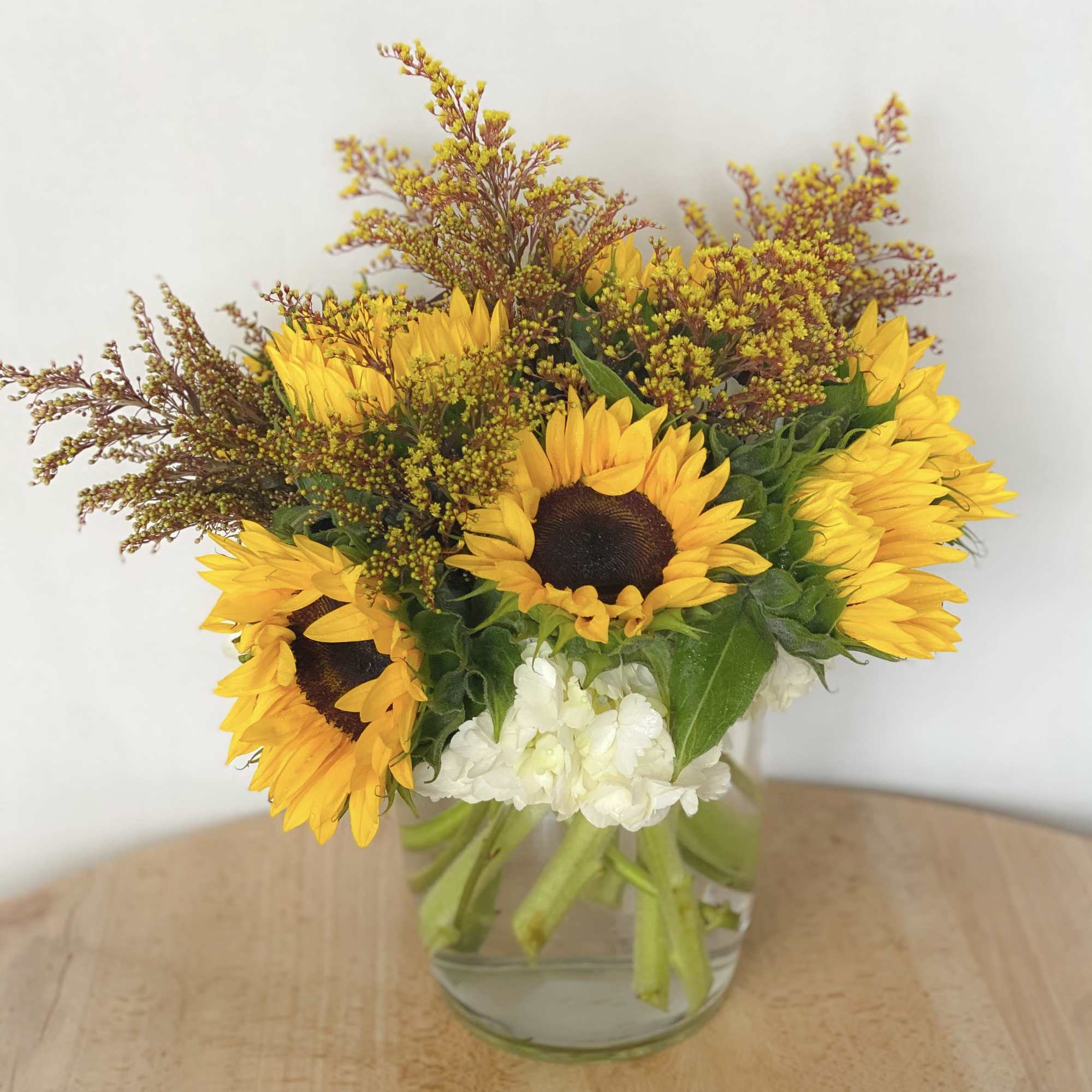 Fully bloomed sunflowers elegantly arranged on a bed of premium white hydrangeas