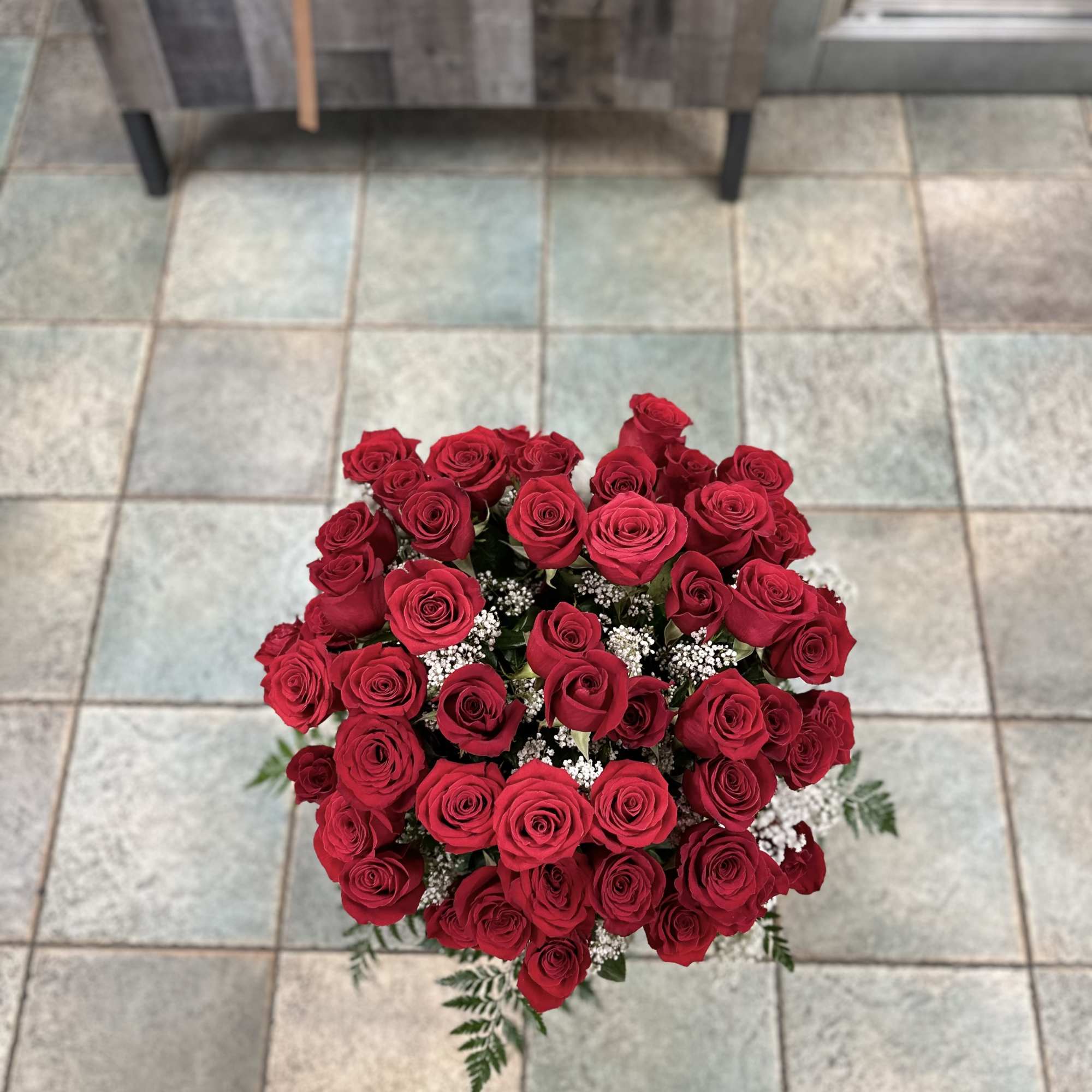 Long-stem roses in a vase filled with baby breath and greens with