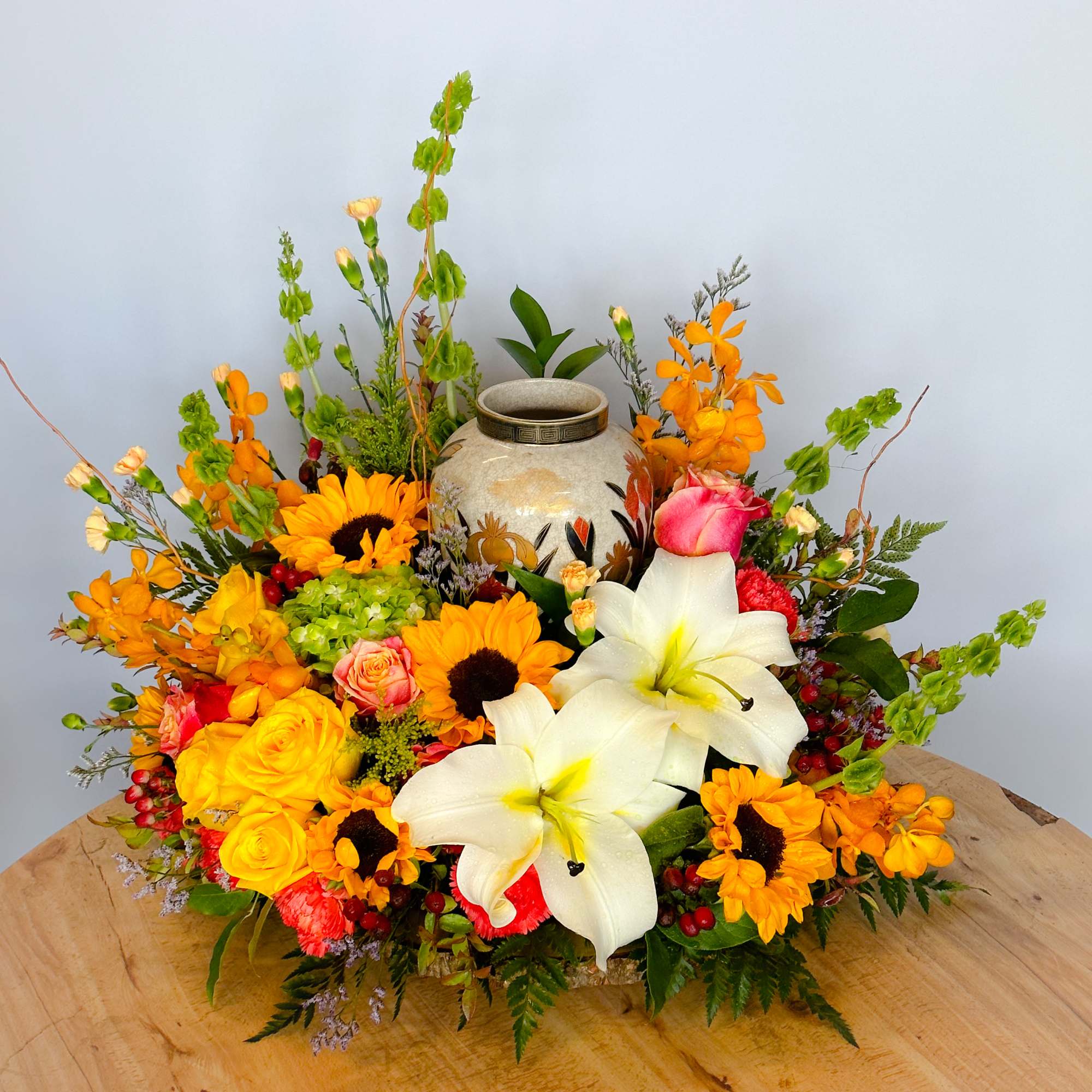 This colorful arrangement cradles the urn in a vibrant embrace of bright