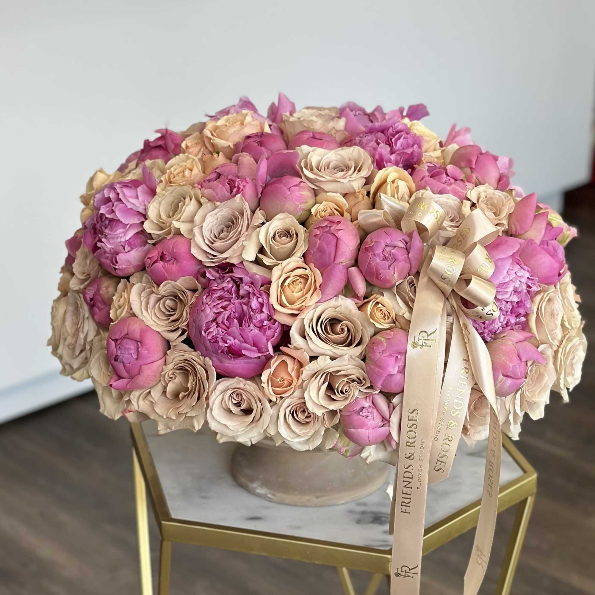 A vintage vase filled with bold peonies and quicksand roses - a