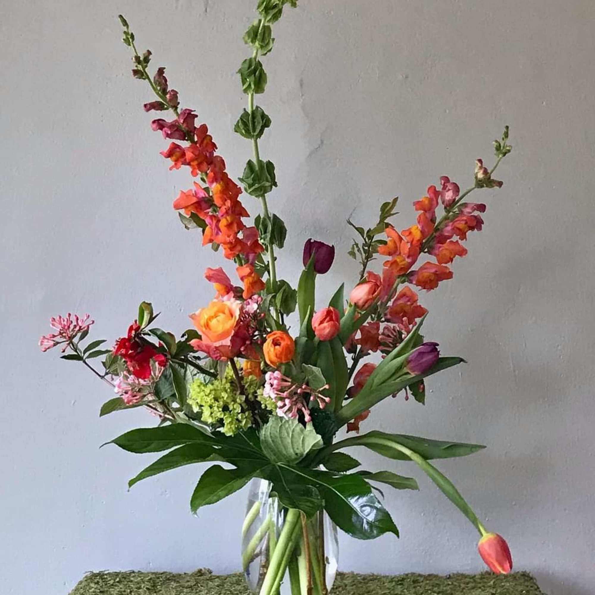 This beauty incorporates a warm palette of snap-dragons, tulips, green hydrangeas, and