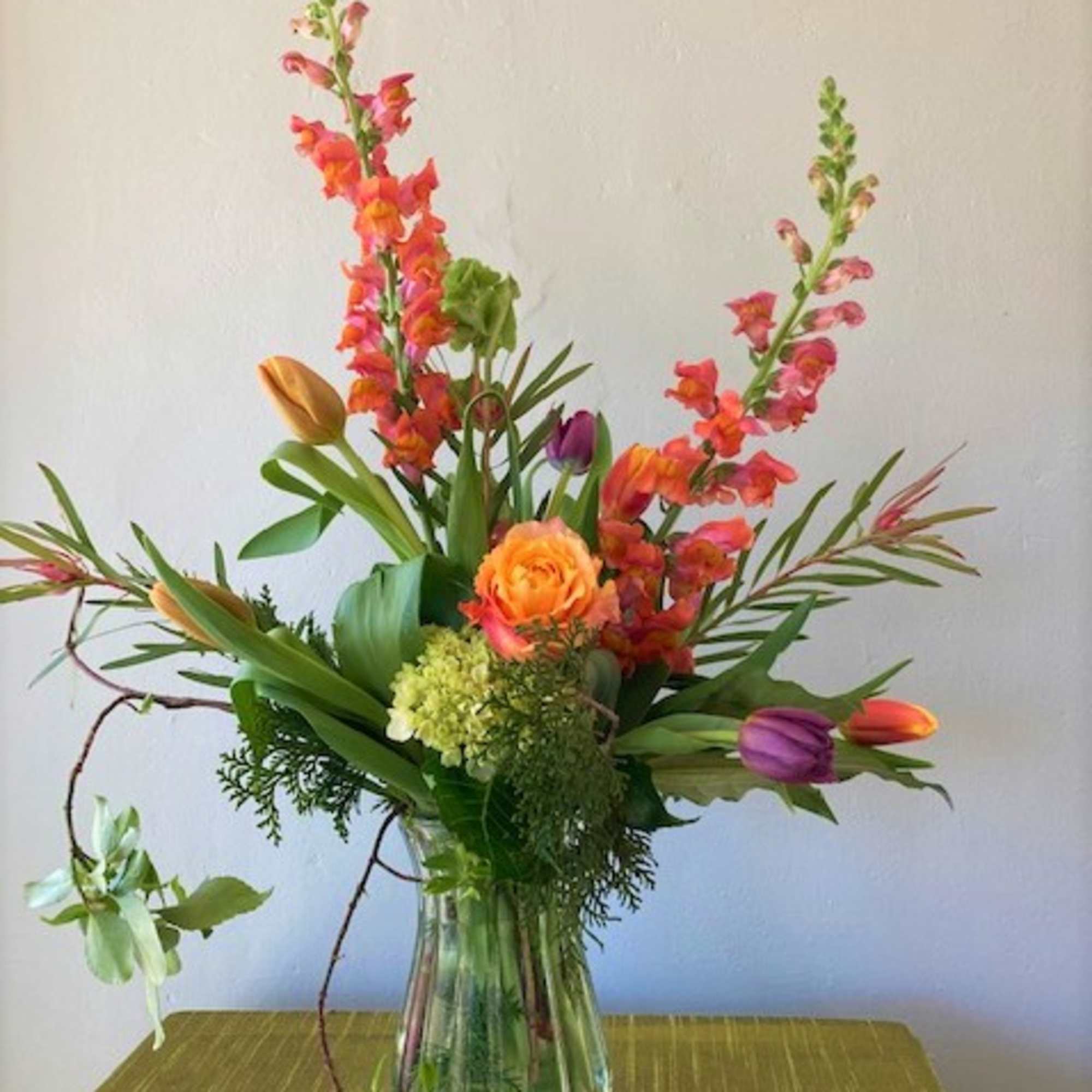This beauty incorporates a warm palette of snap-dragons, tulips, green hydrangeas, and