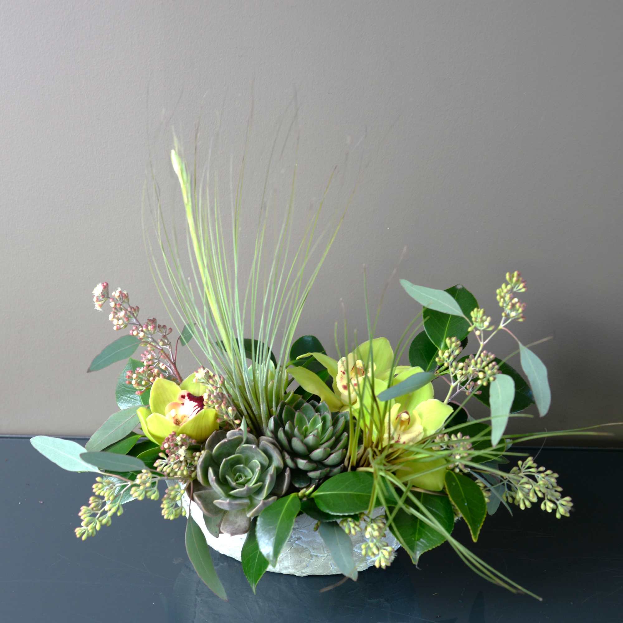 This arrangement is a melting pot of tropical orchids, desert loving succulents This arrangement is a melting pot of tropical orchids, desert loving succulents