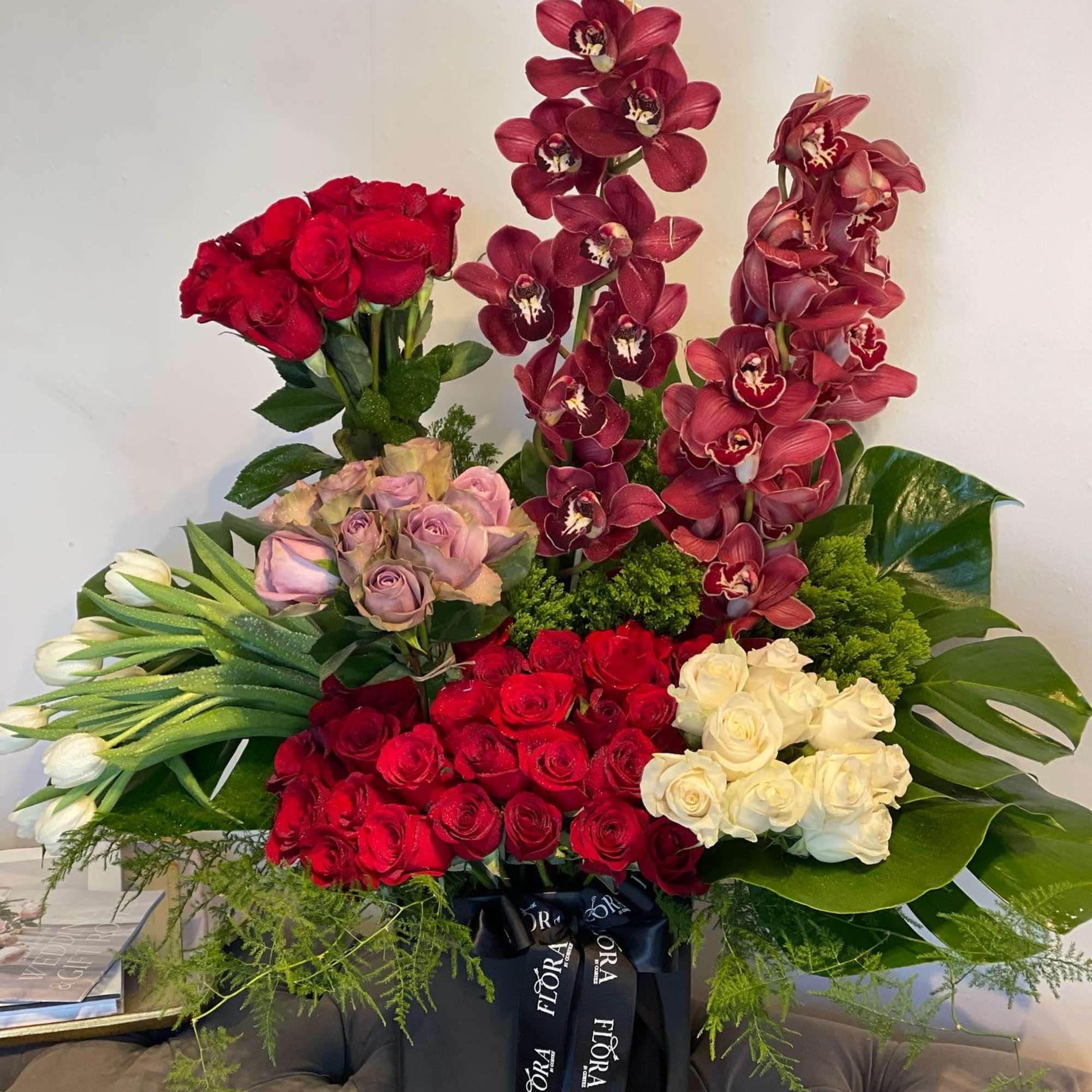 Beautiful floral garden arrangement featuring red and white roses, tulips, cymbidium orchids