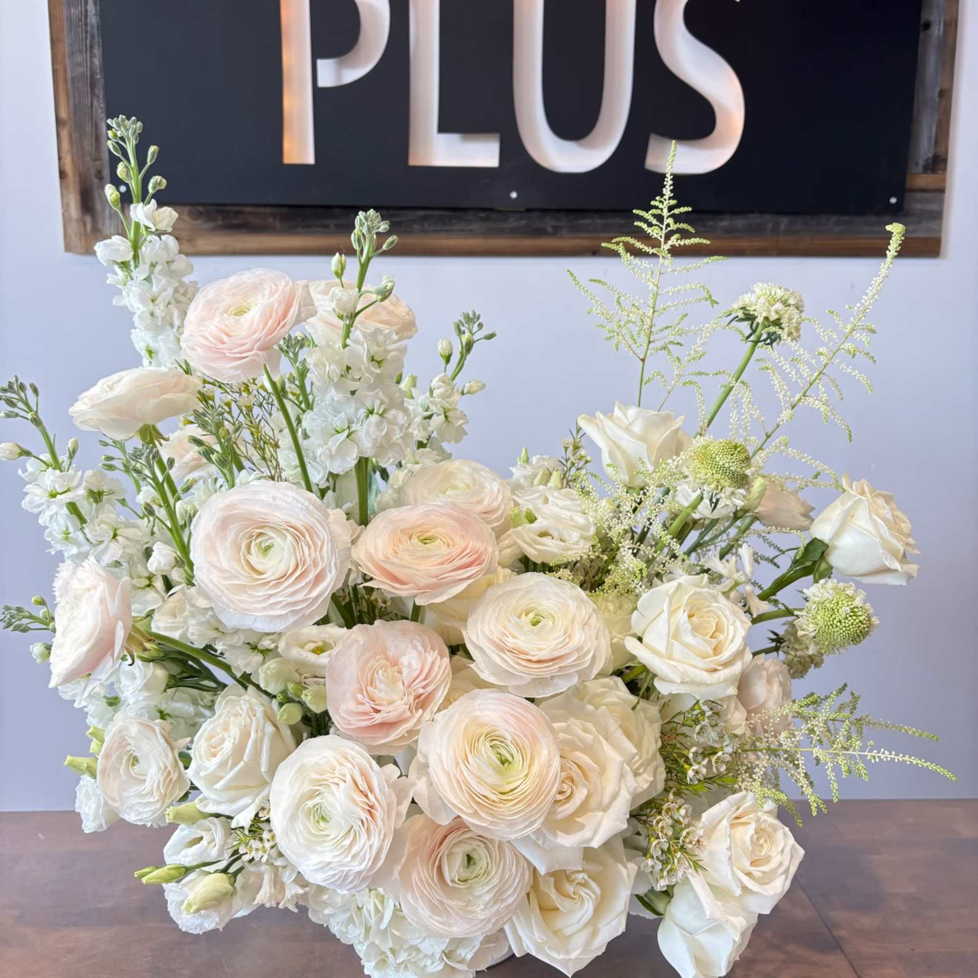A grand and elegant arrangement featuring lush white and blush ranunculus, garden