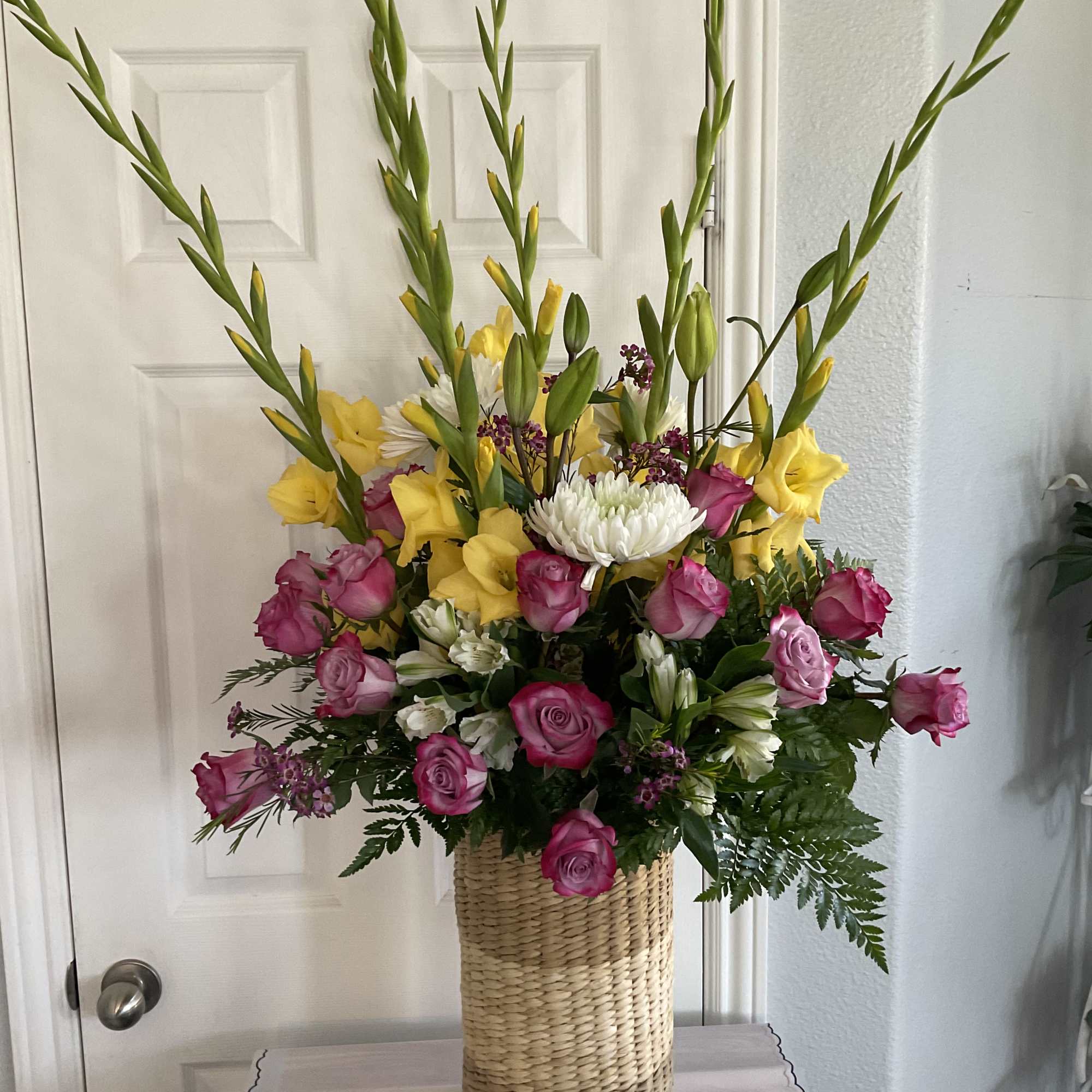 Very large in a clear vase , gladiolus, roses, spray roses, with