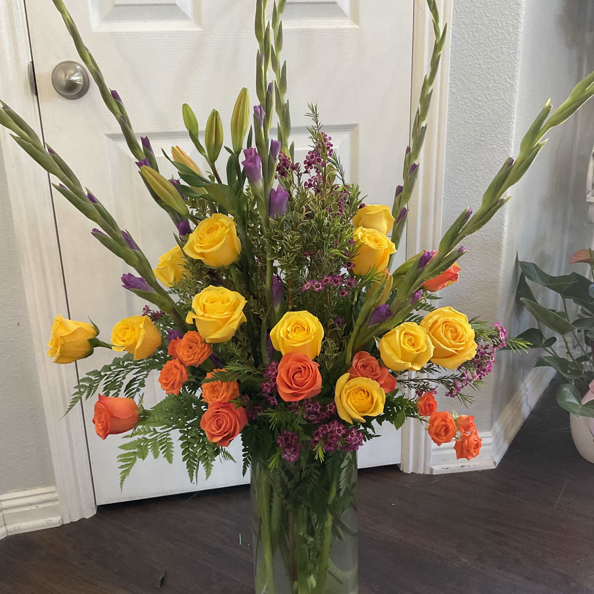 Very large in a clear vase , gladiolus, roses, spray roses, with
