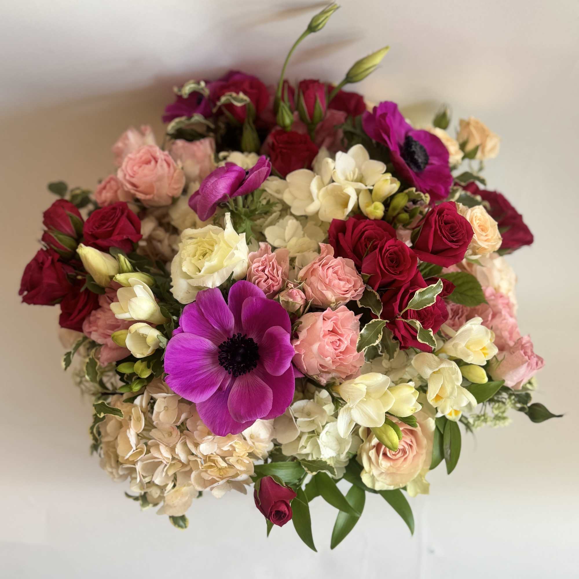 A sweet arrangement with anemones, roses, lisianthus, and hydrangea. 