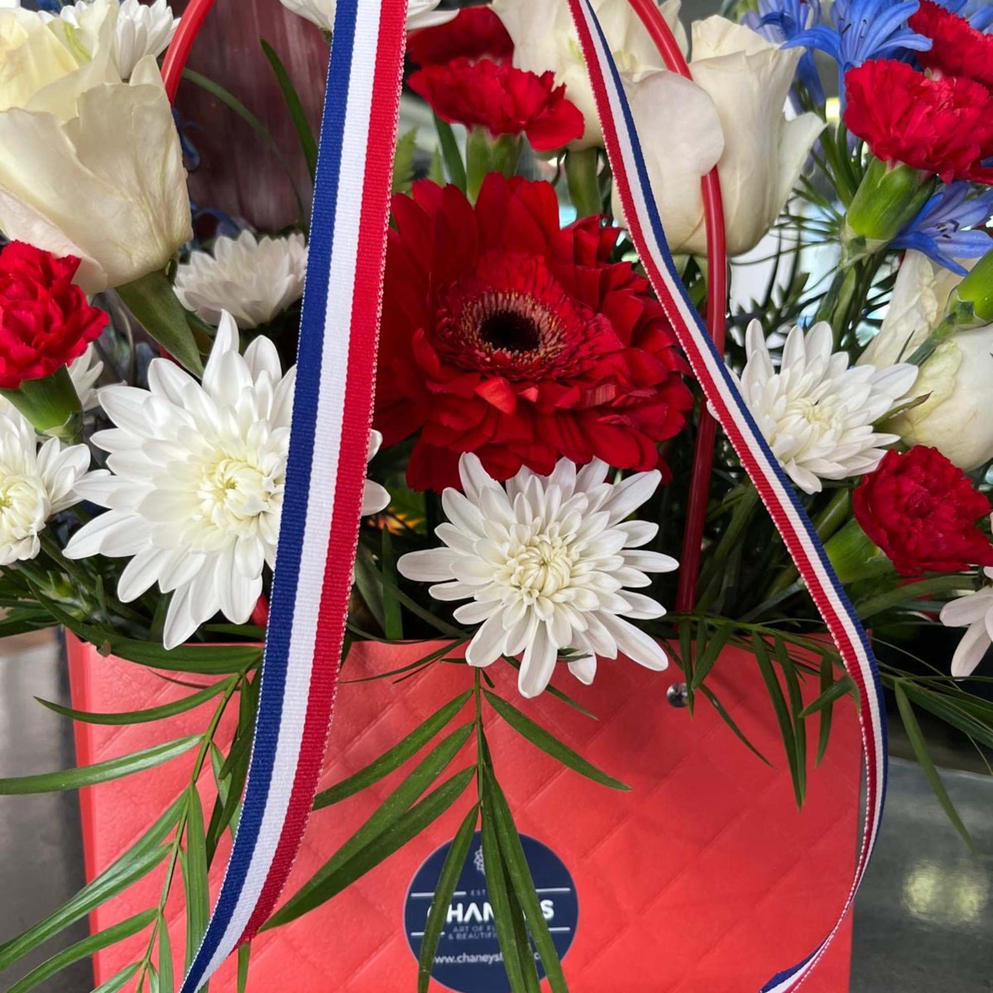A cute purse in Red, White and Blue with Premium flowers
