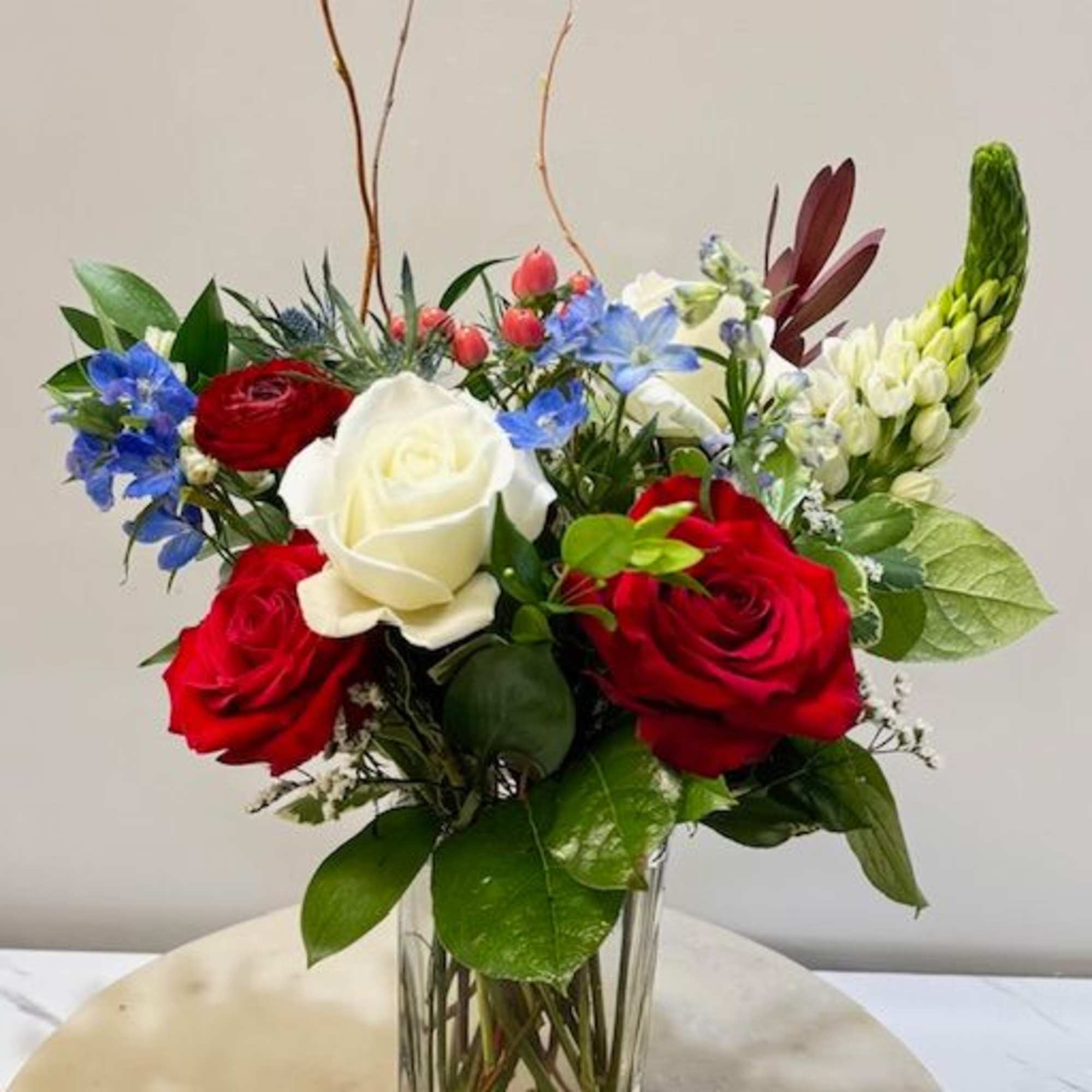 A vibrant mix of red roses, white blooms, and soft blue accents. A vibrant mix of red roses, white blooms, and soft blue accents.