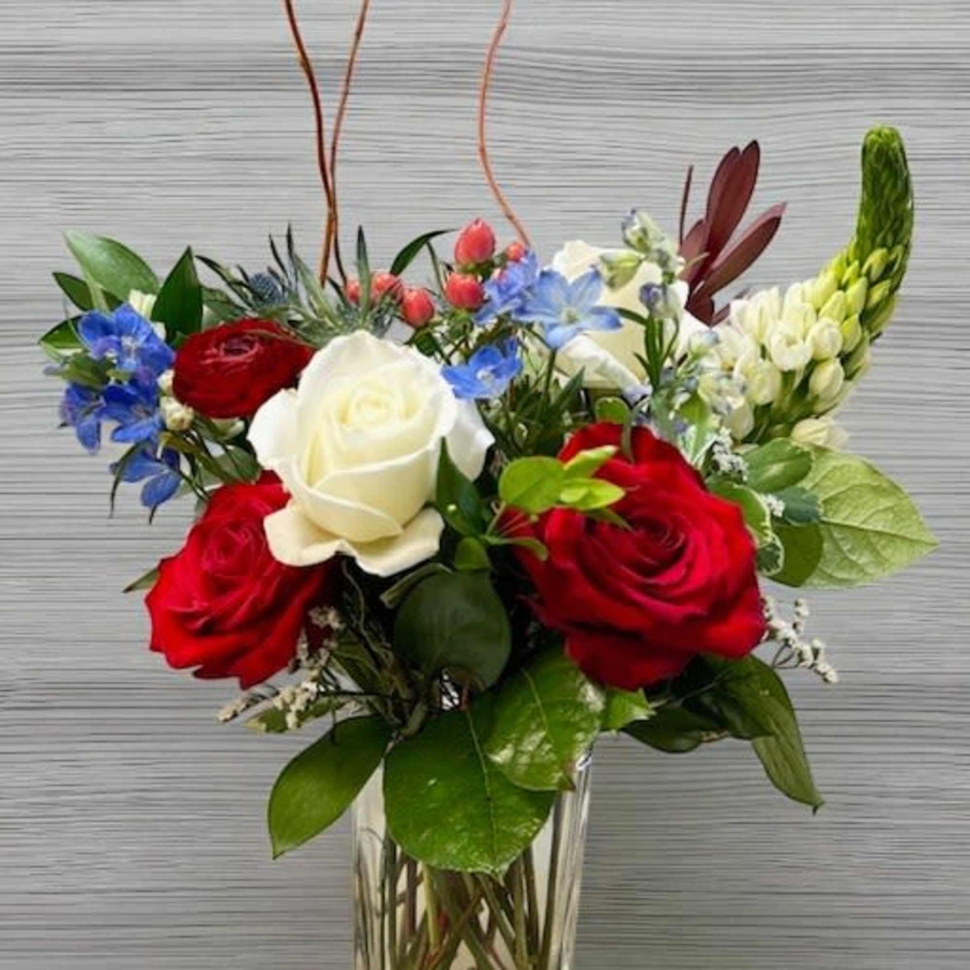 A vibrant mix of red roses, white blooms, and soft blue accents. A vibrant mix of red roses, white blooms, and soft blue accents.