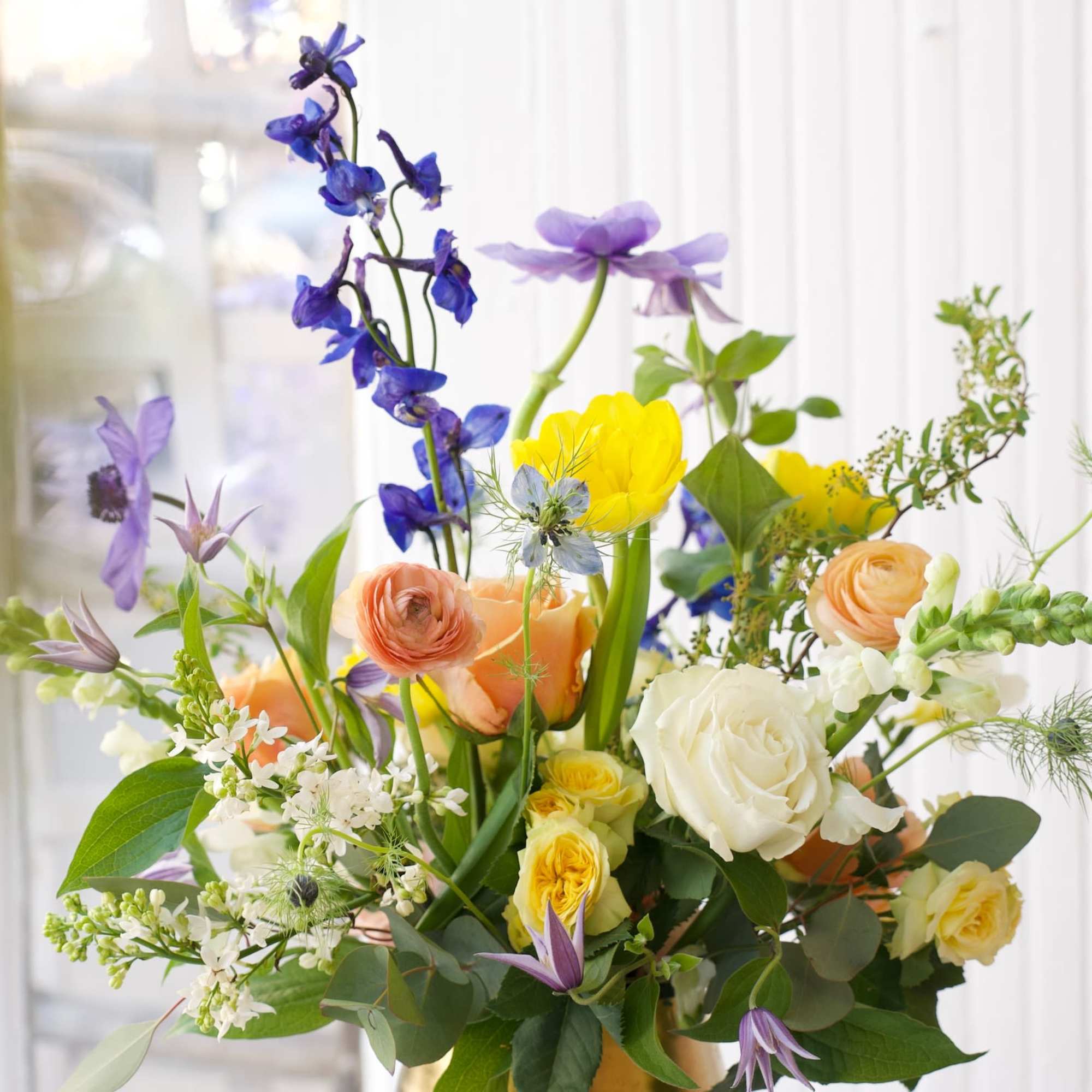 A dreamy blend of delphinium, anemones, roses, and ranunculus—soft hues and bright A dreamy blend of delphinium, anemones, roses, and ranunculus—soft hues and bright
