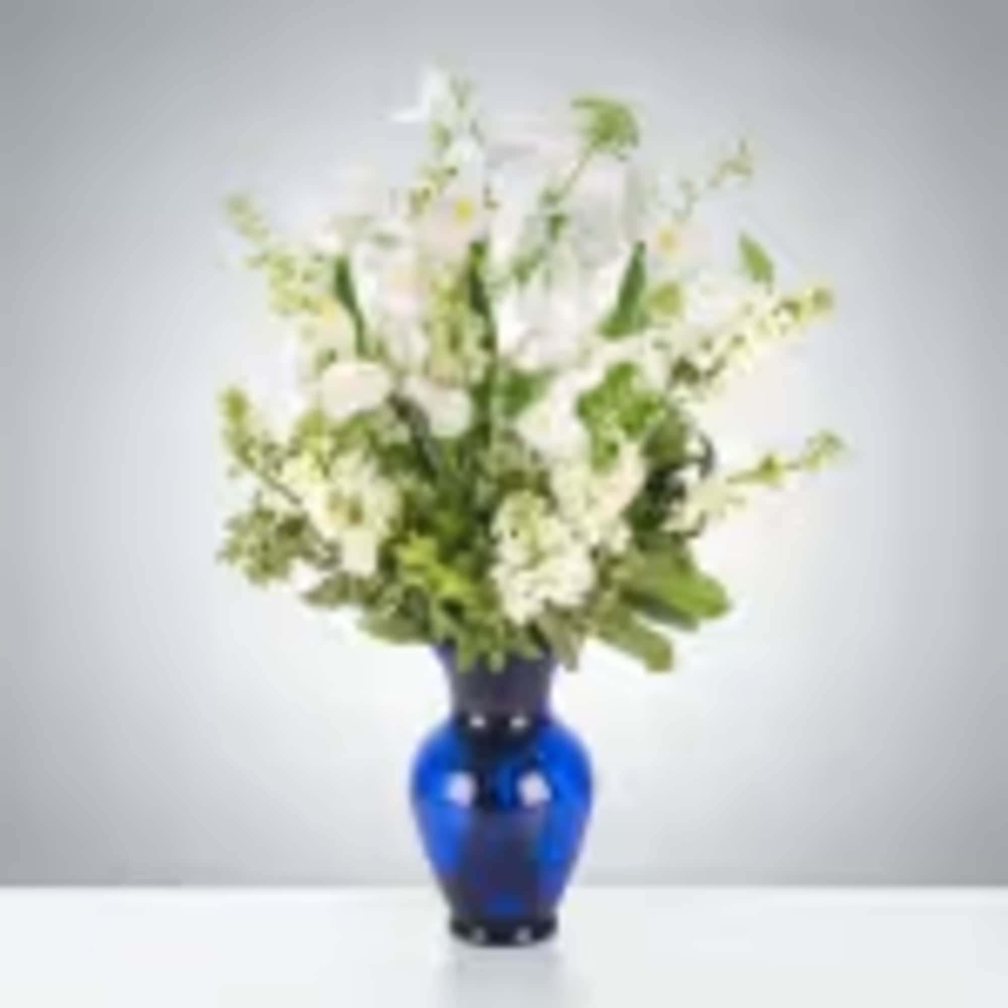 This arrangement includes white iris, white stock, white snapdragons, and queen anne&#039;s