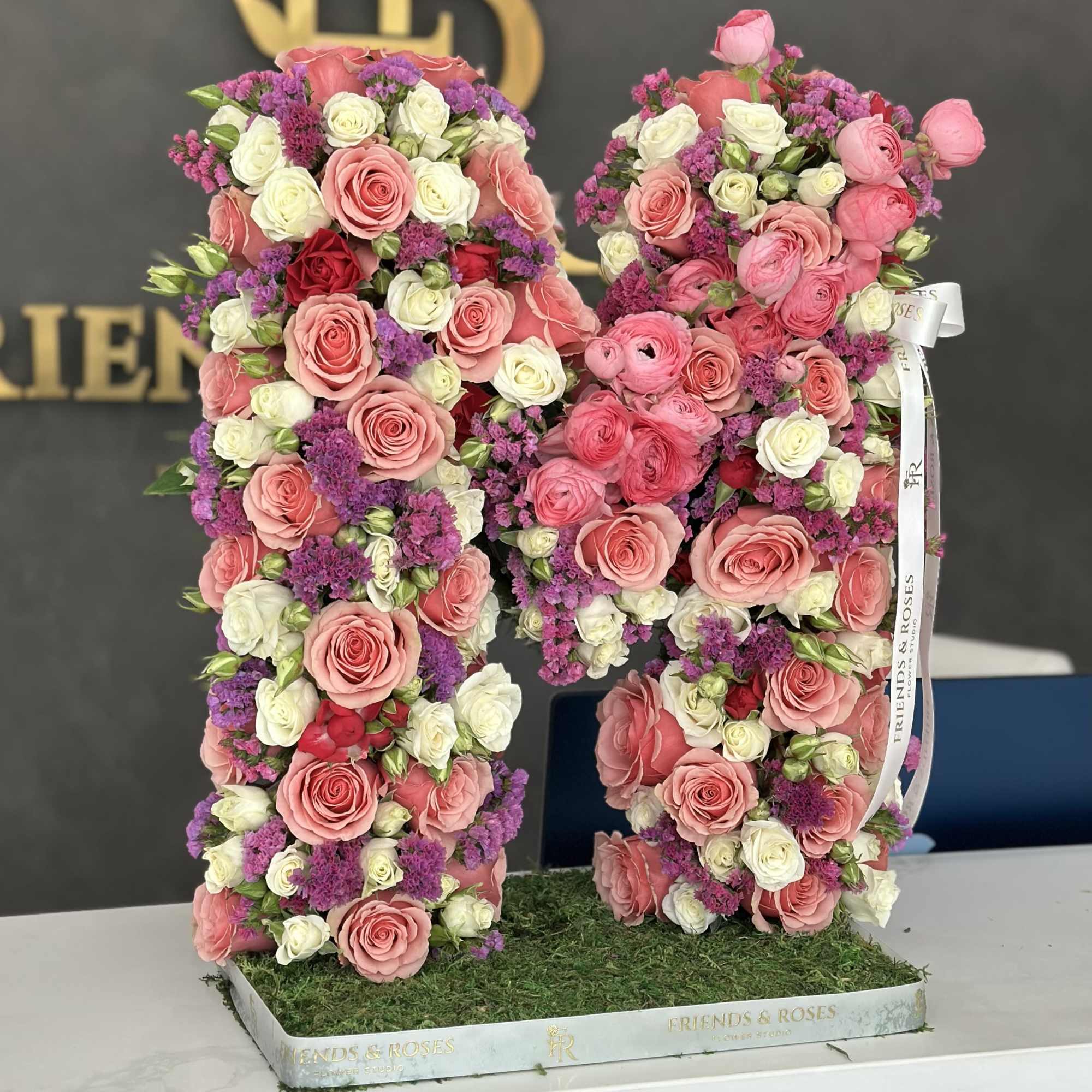 A floristic composition in the shape of the letter M features a