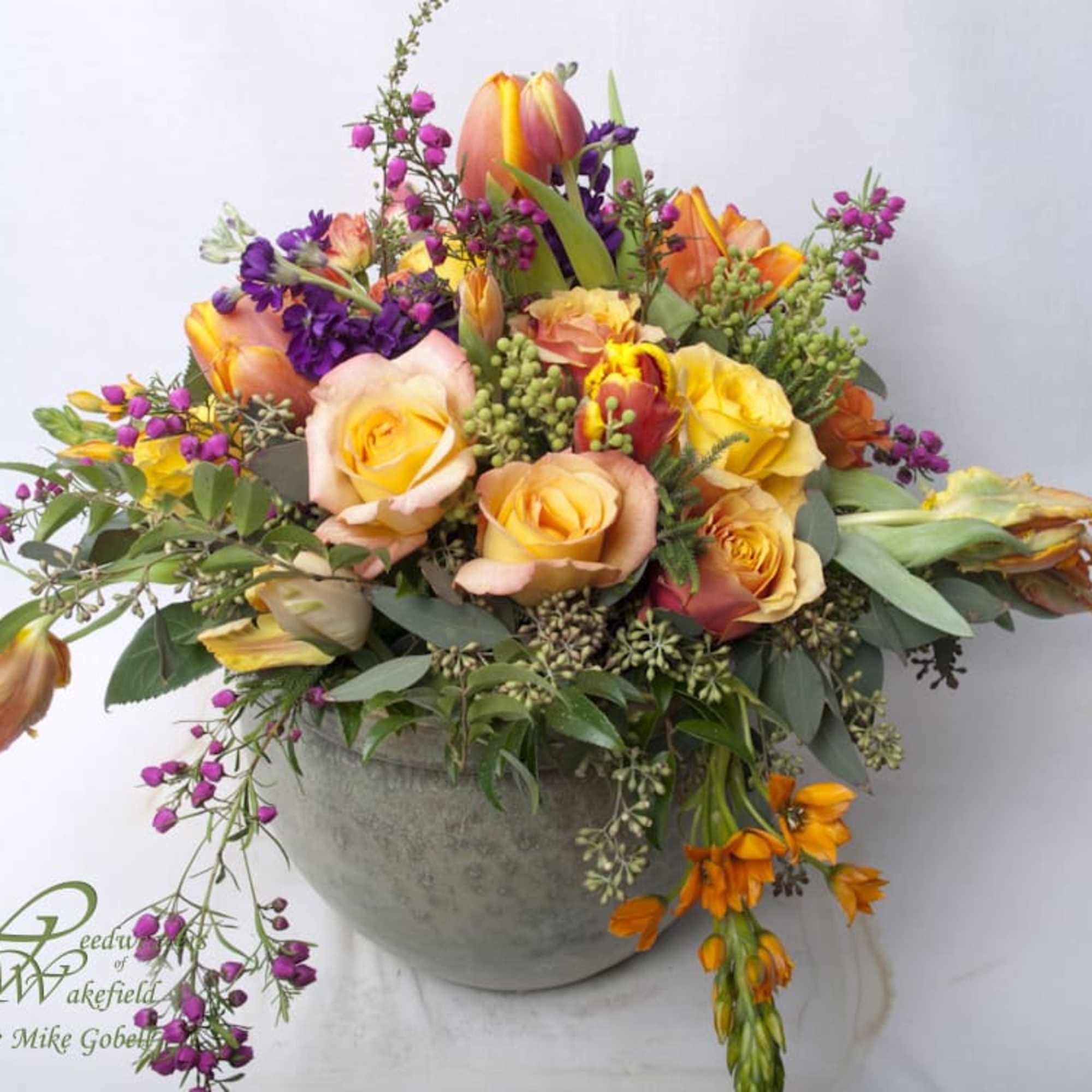 Send this lush, rich assortment of flowers in a glazed ceramic pot