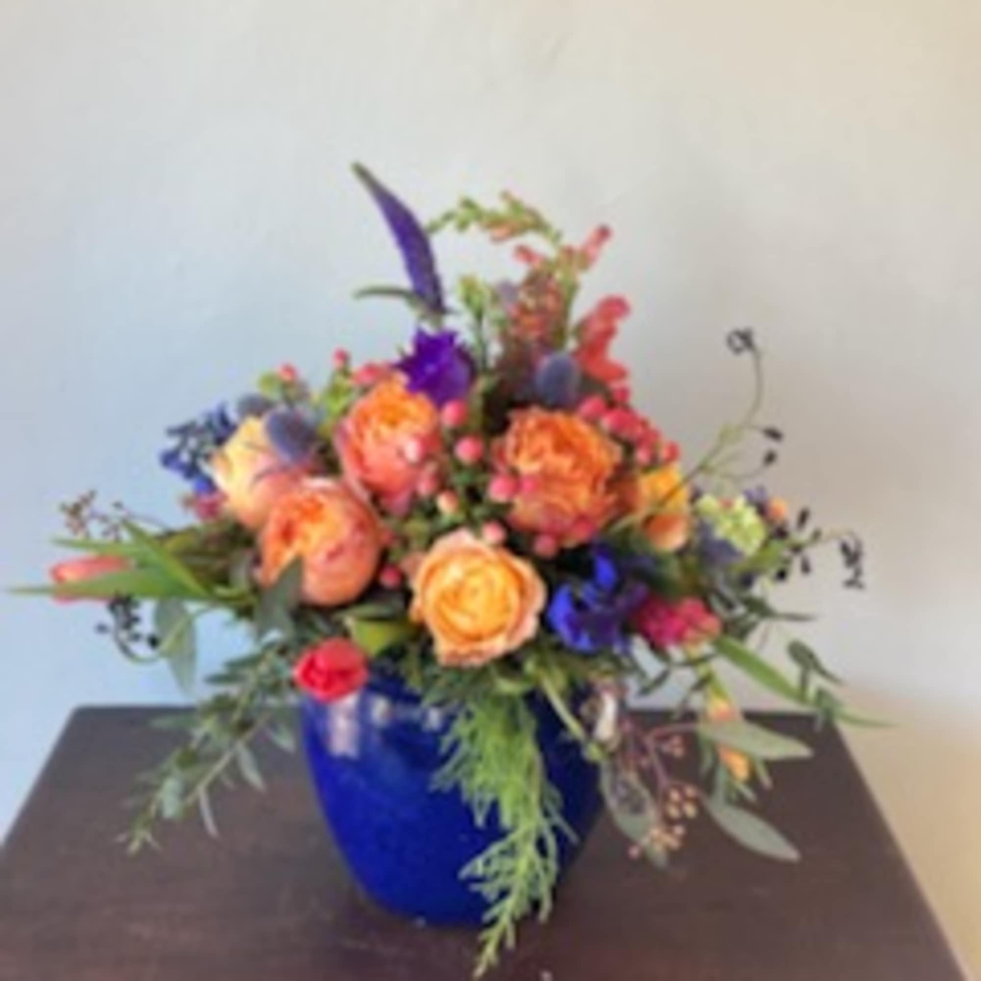 Send this lush, rich assortment of flowers in a glazed ceramic pot