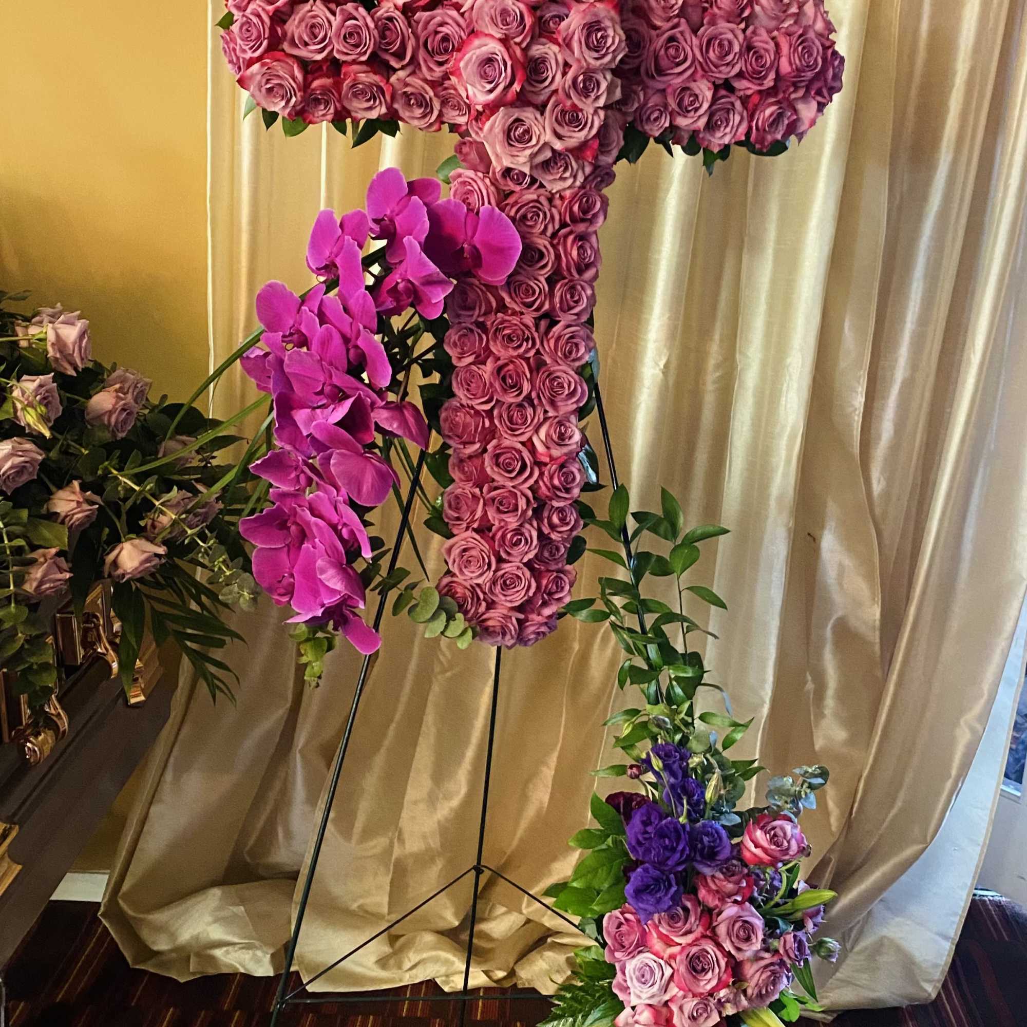 A breathtaking standing cross of majestic purple and lavender blooms remembers and