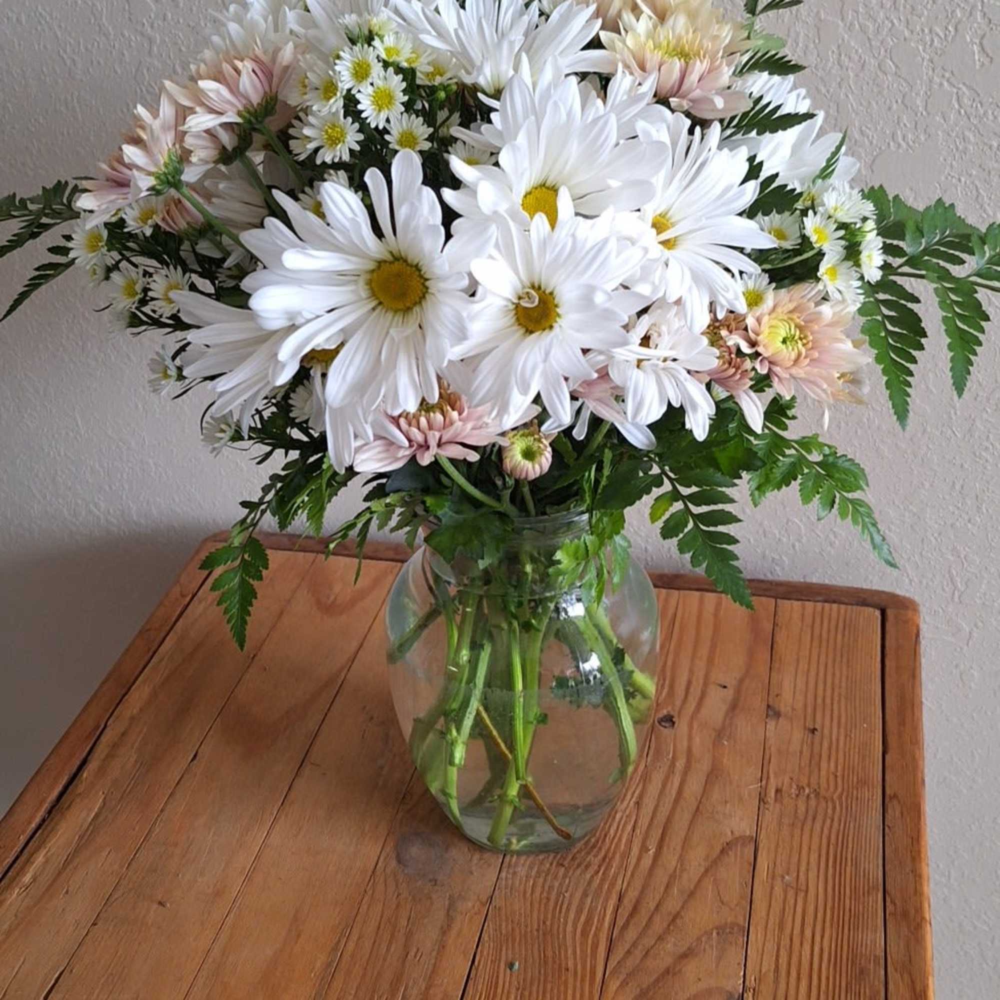 A sparkling glass vase overflowing with sun-kissed daisies is a sure-fire way