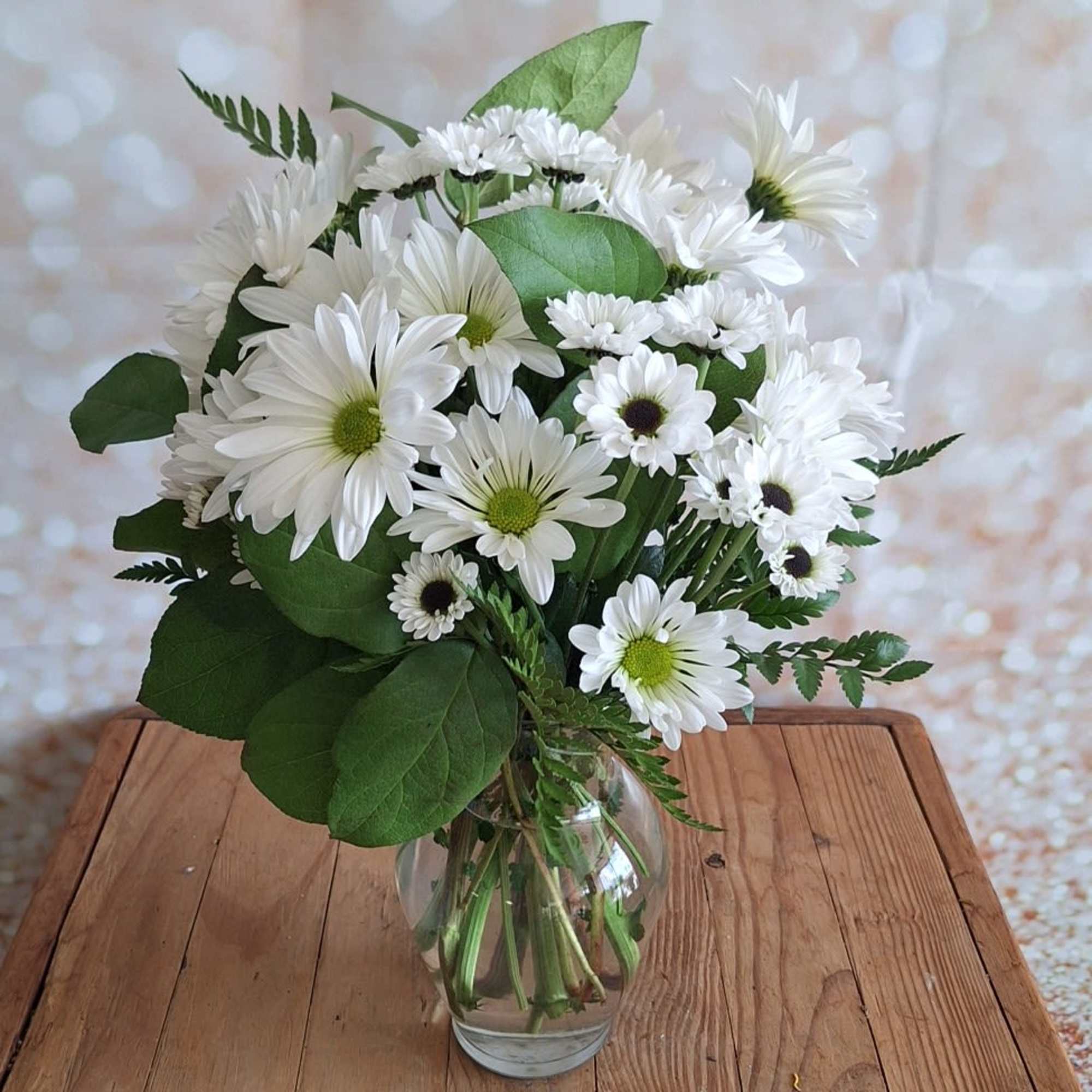 A sparkling glass vase overflowing with sun-kissed daisies is a sure-fire way