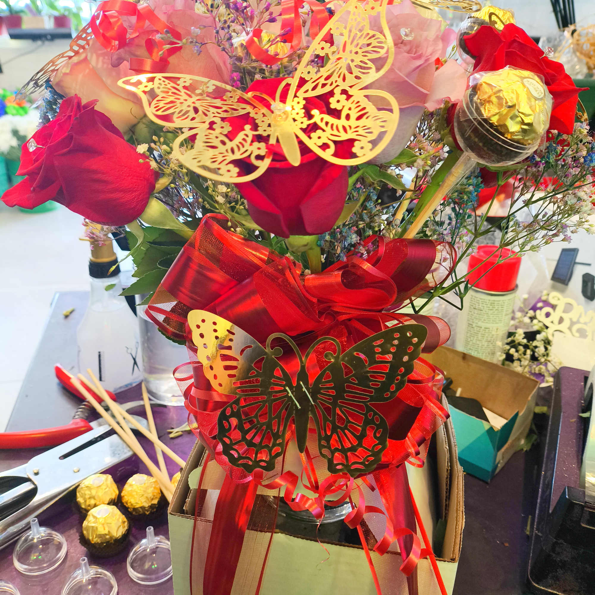 We design a dozen mixed roses in a vase with gold butterflies We design a dozen mixed roses in a vase with gold butterflies