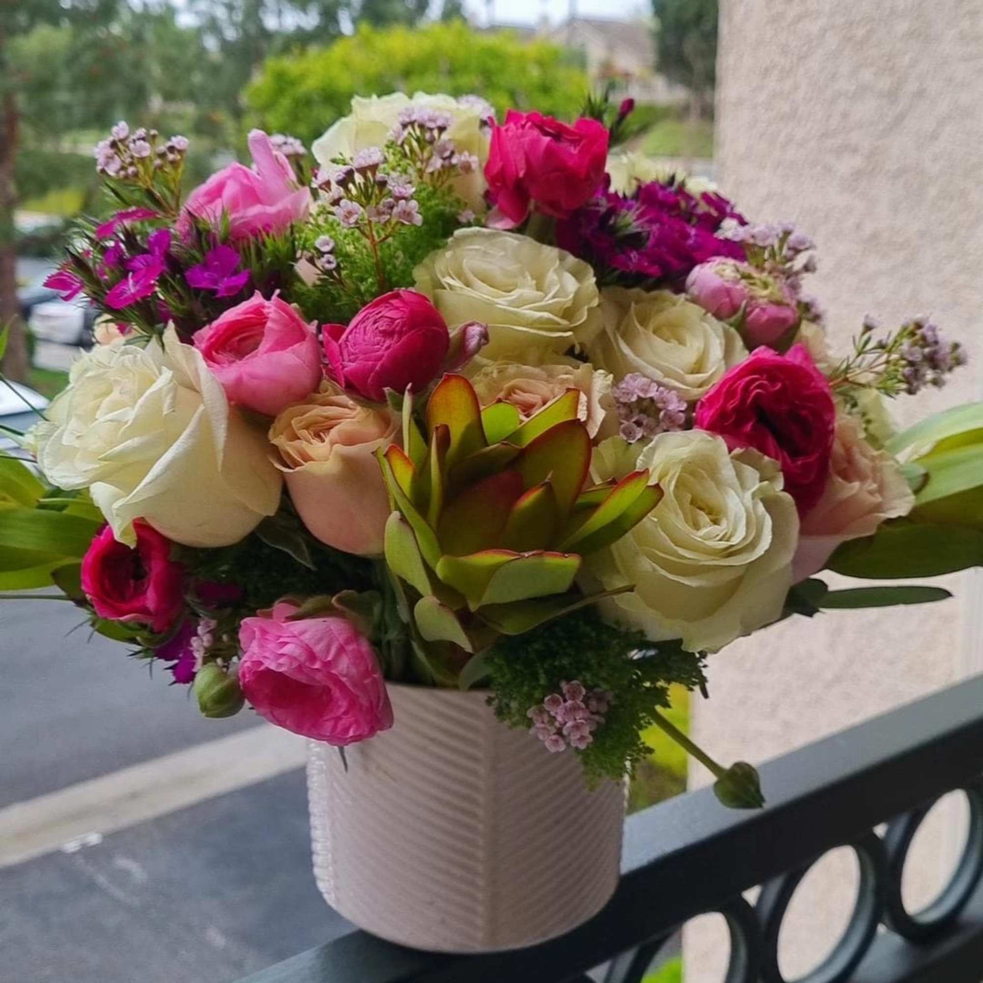 The bouquet includes a mix of white, pink, and deep magenta roses