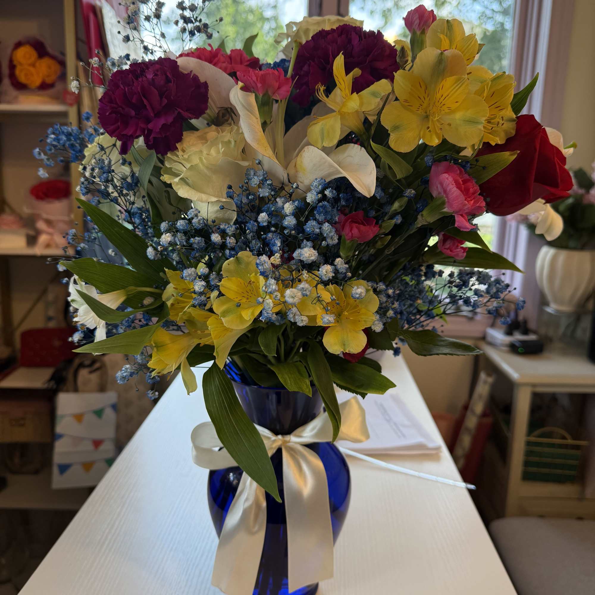 Beautiful mix flowers with blue baby breath in a classic blue vase.
