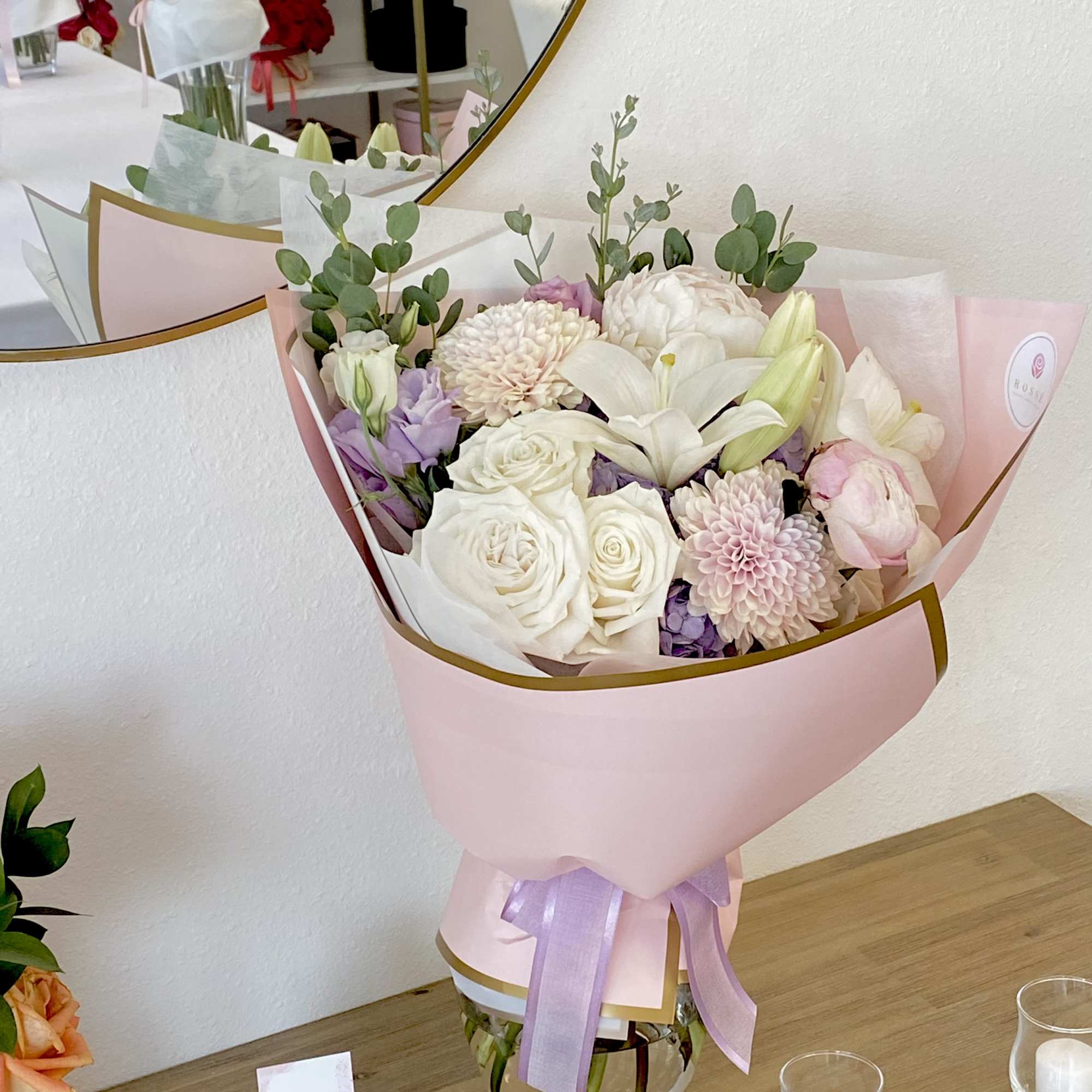A front-facing bouquet with white flowers and greenery, wrapped in white paper.
