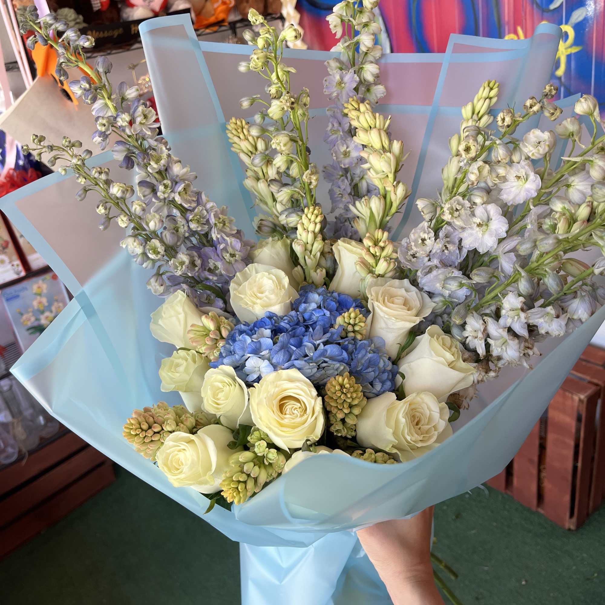 mix of tuberose; delphinium; and roses, with a hydrangea in the center
