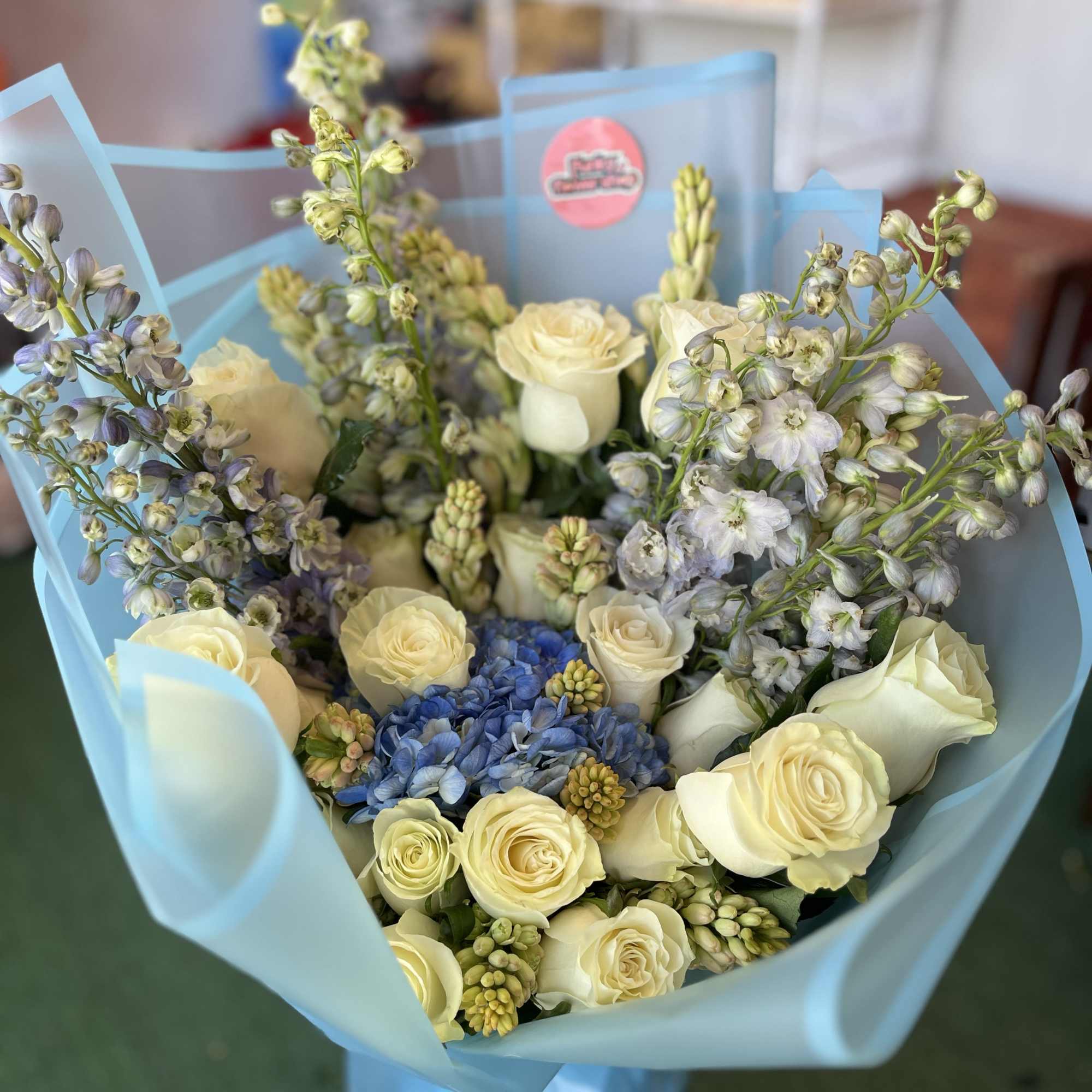 mix of tuberose; delphinium; and roses, with a hydrangea in the center