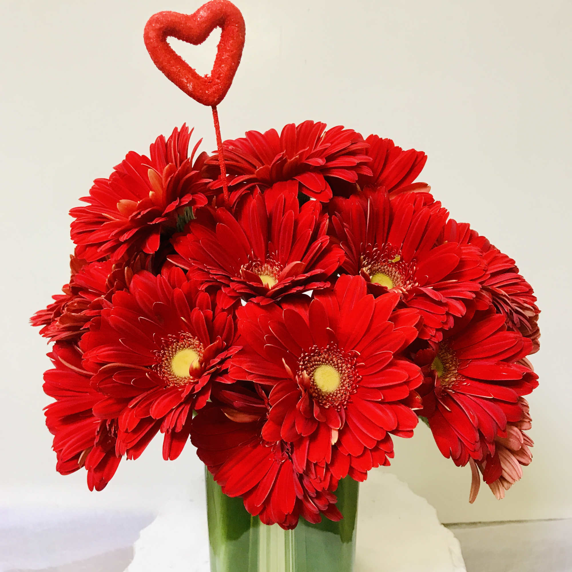 Nice glass vase with a green leaf inside and 15 red Gerber