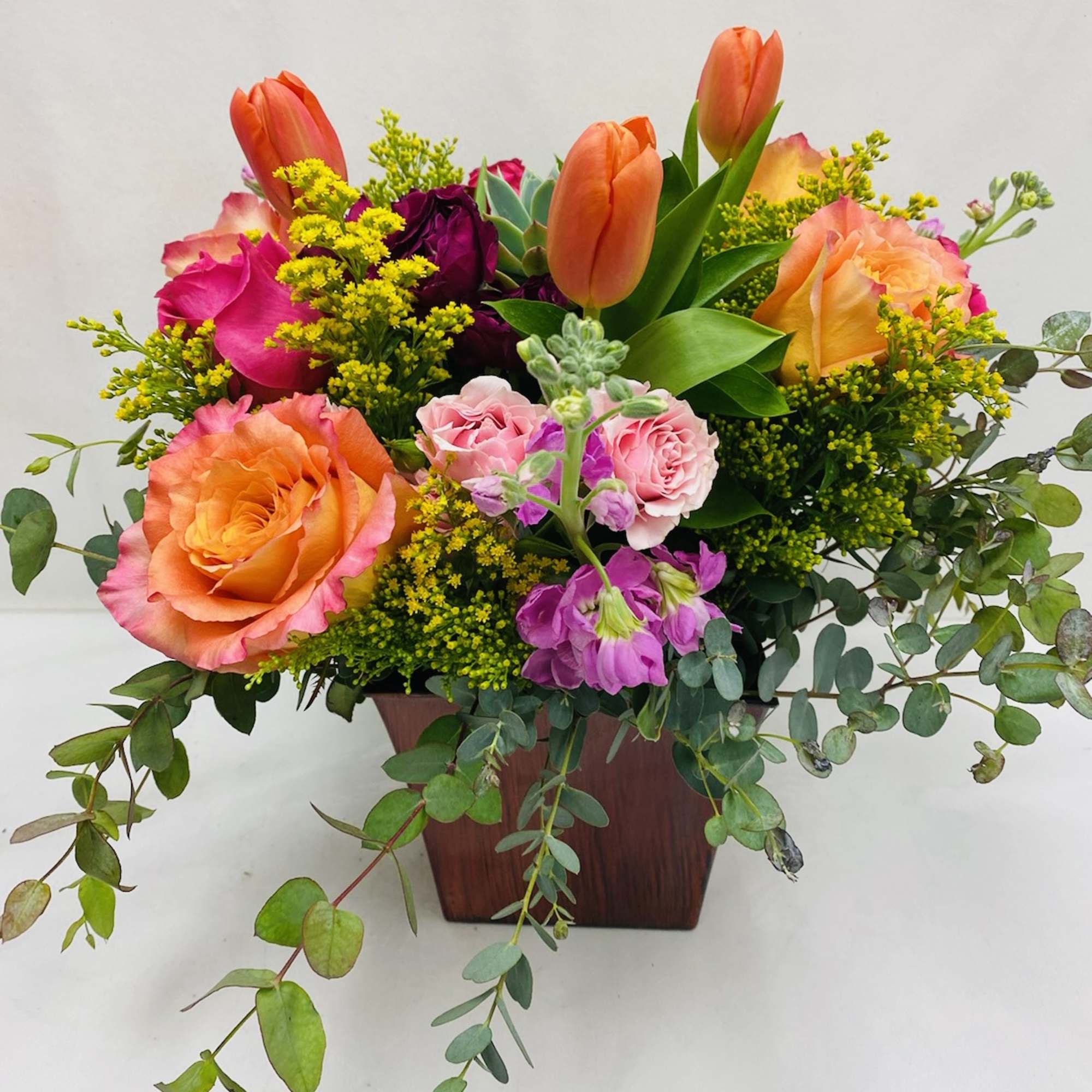 Centrally placed succulent surrounded by brightly colored selection of flowers including Roses