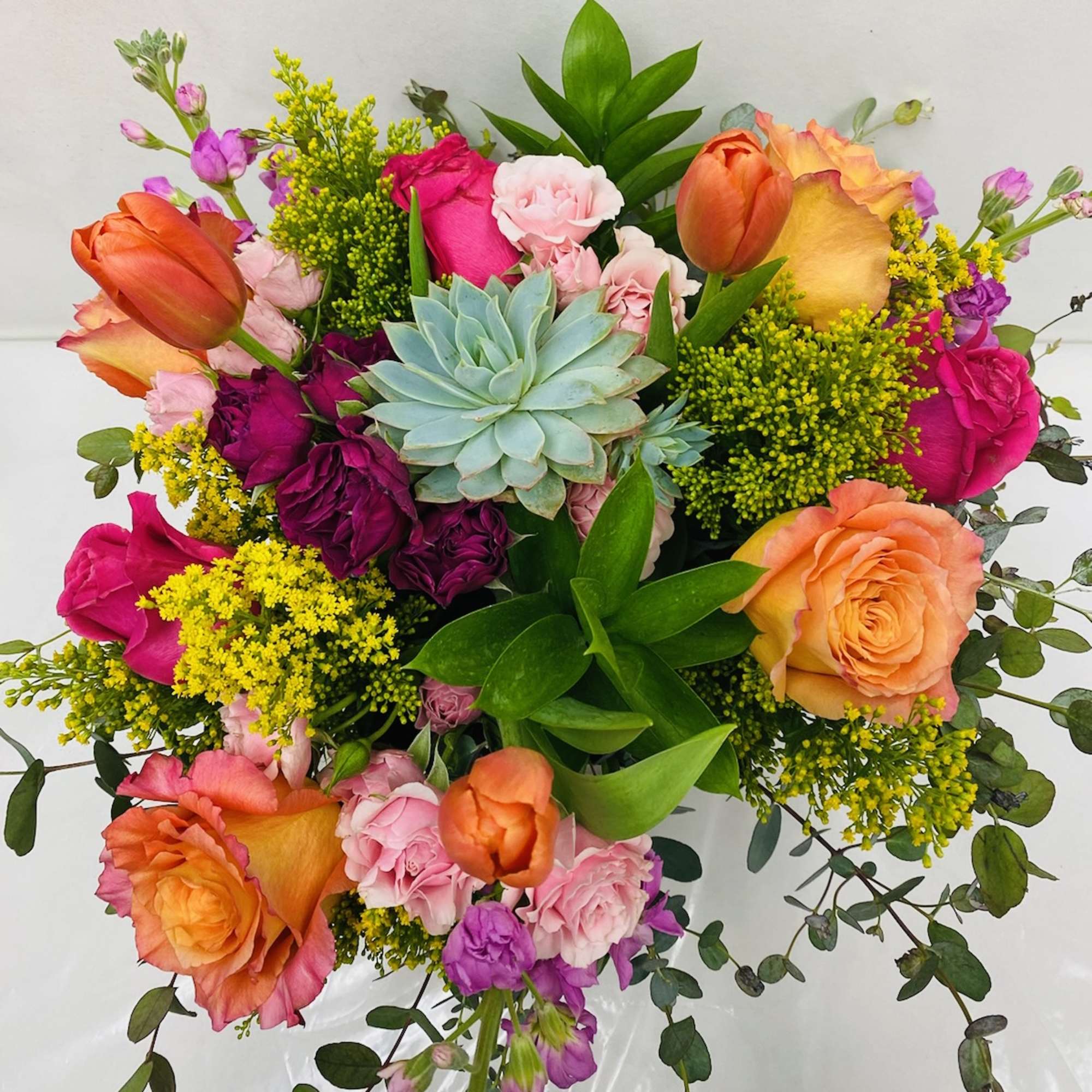Centrally placed succulent surrounded by brightly colored selection of flowers including Roses
