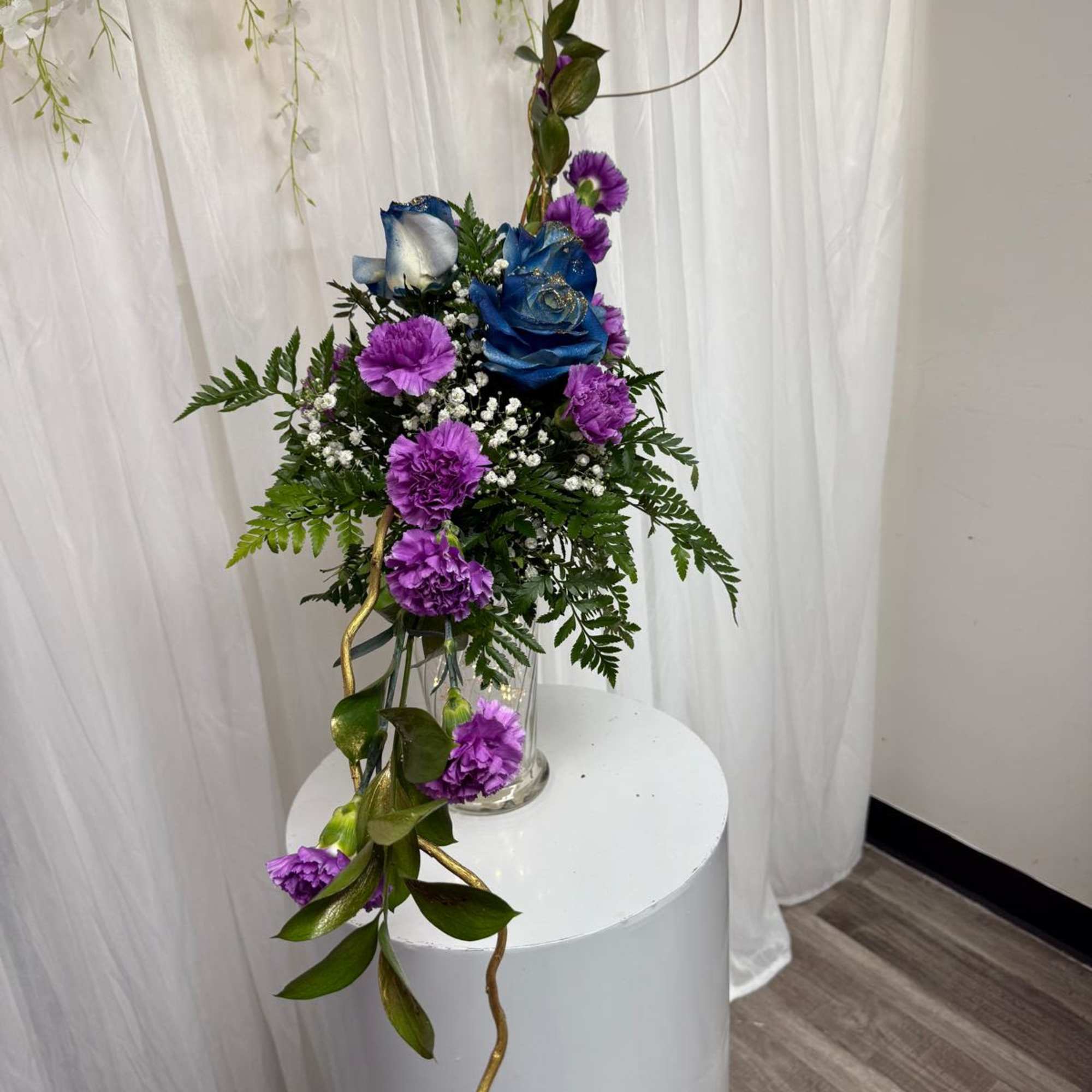 A striking floral arrow featuring bold blue roses and playful purple blooms A striking floral arrow featuring bold blue roses and playful purple blooms