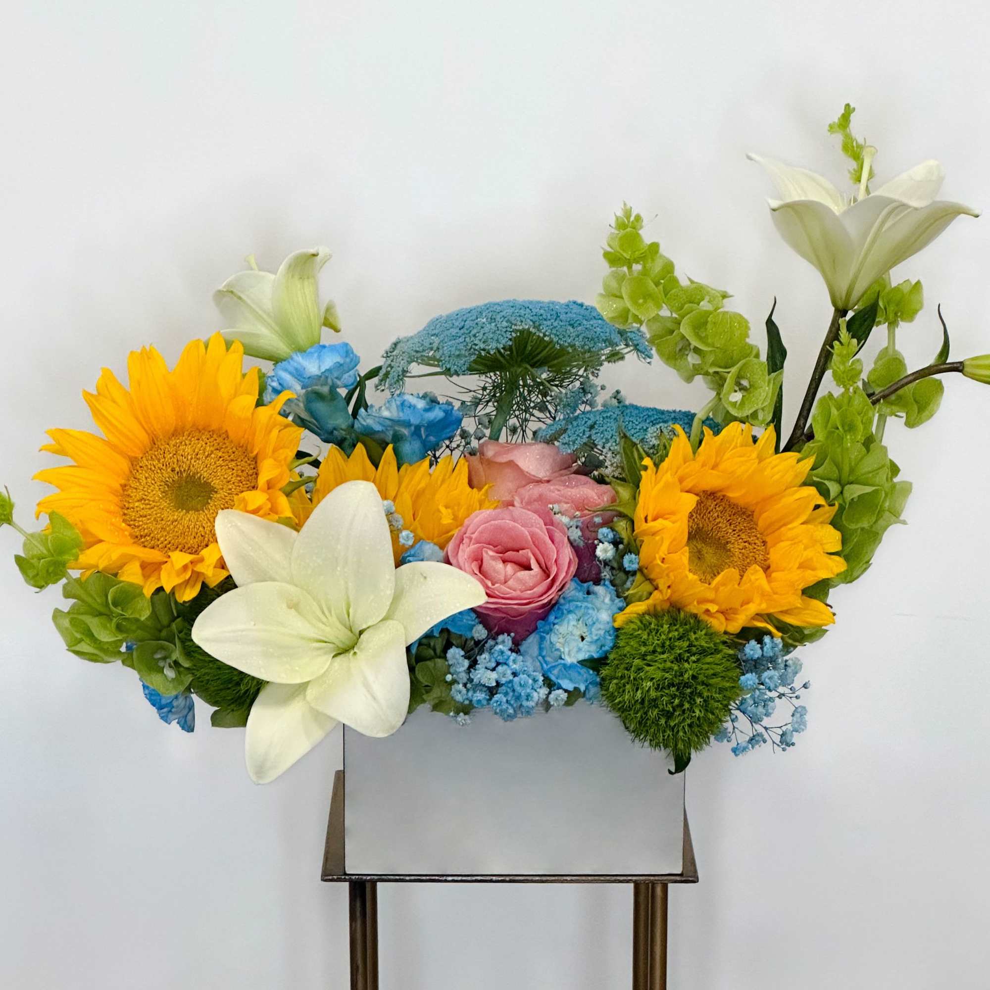 A harmonious blend of vibrant sunflowers, delicate pale blue flowers, and timeless