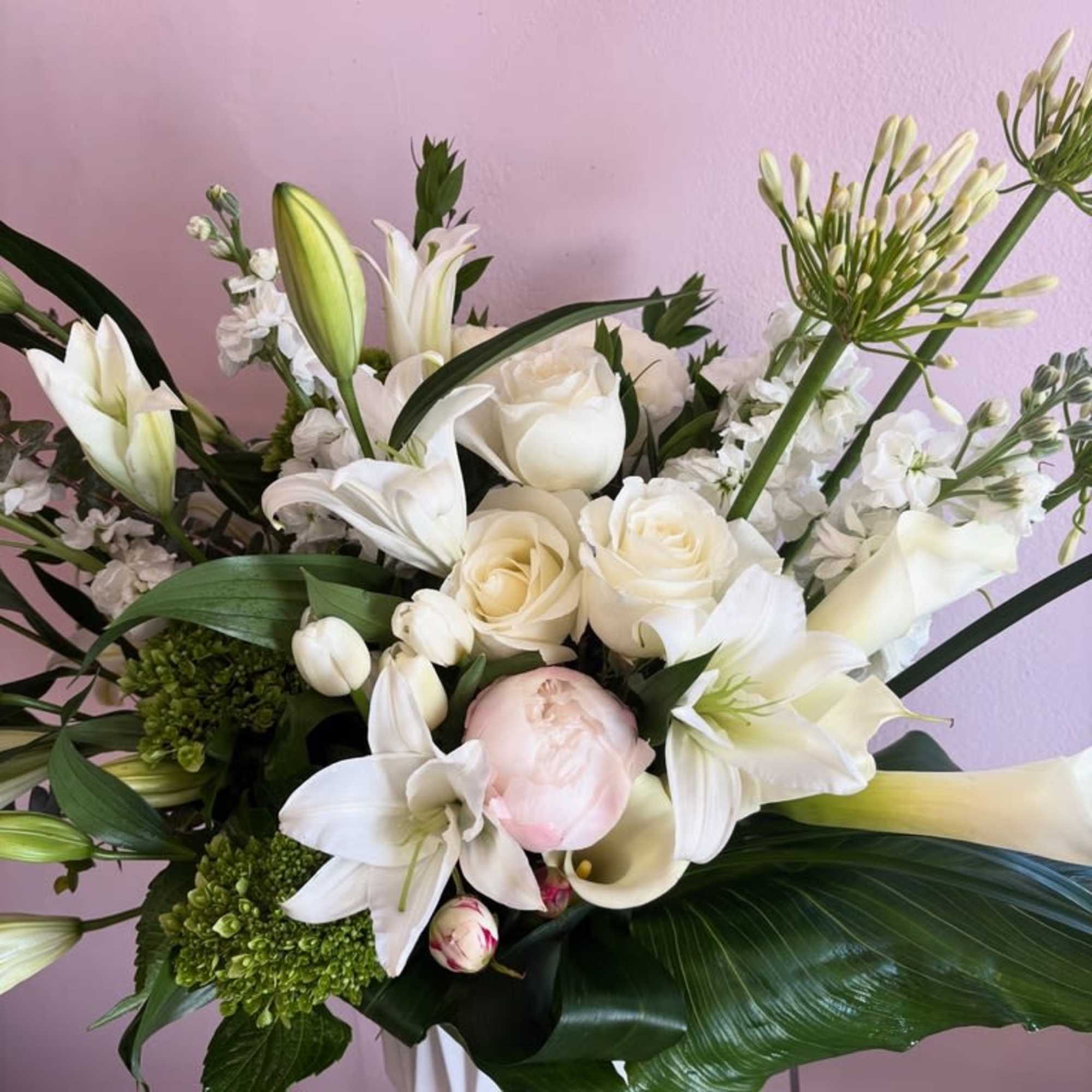 This sophisticated floral arrangement features a stunning medley of pristine white blooms