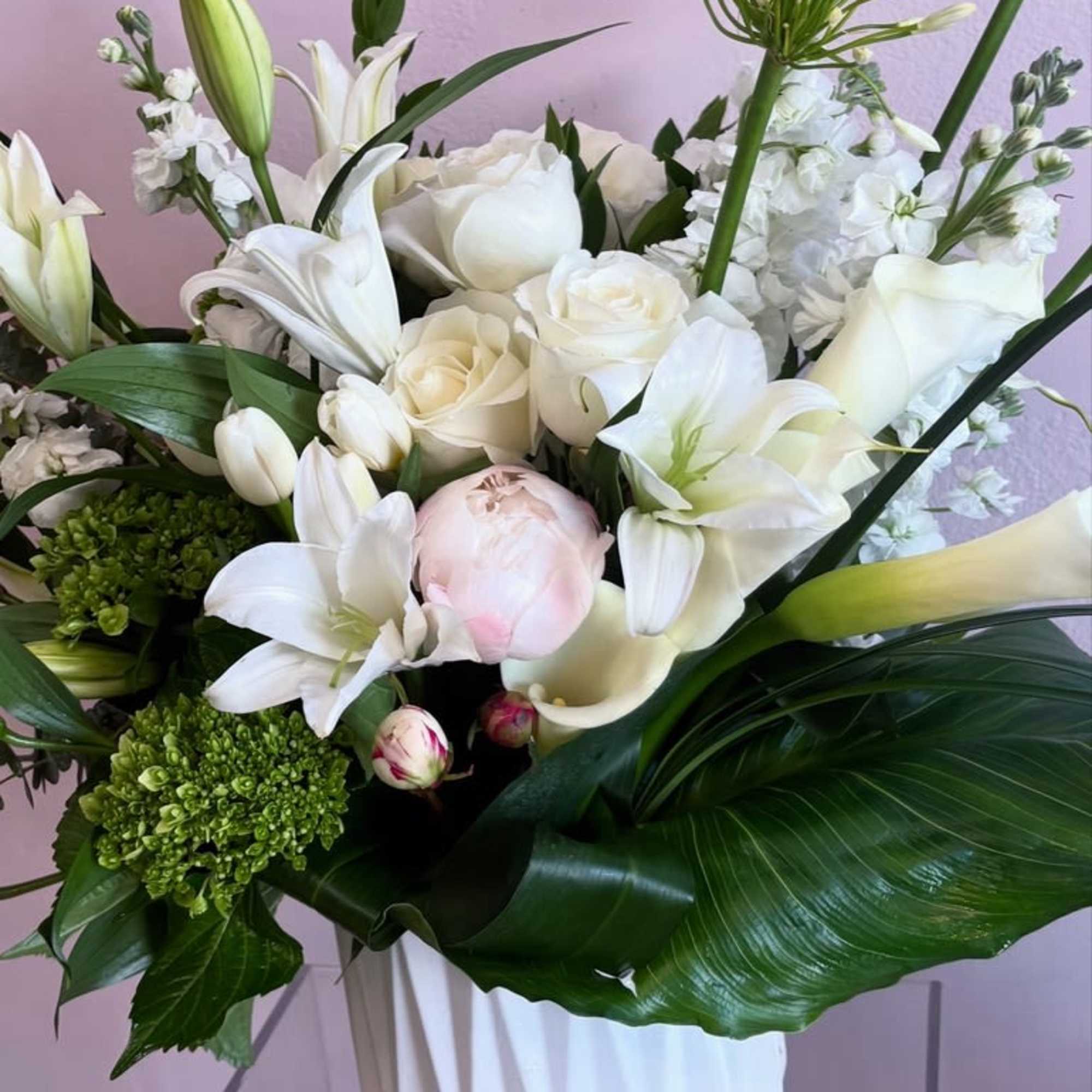 This sophisticated floral arrangement features a stunning medley of pristine white blooms