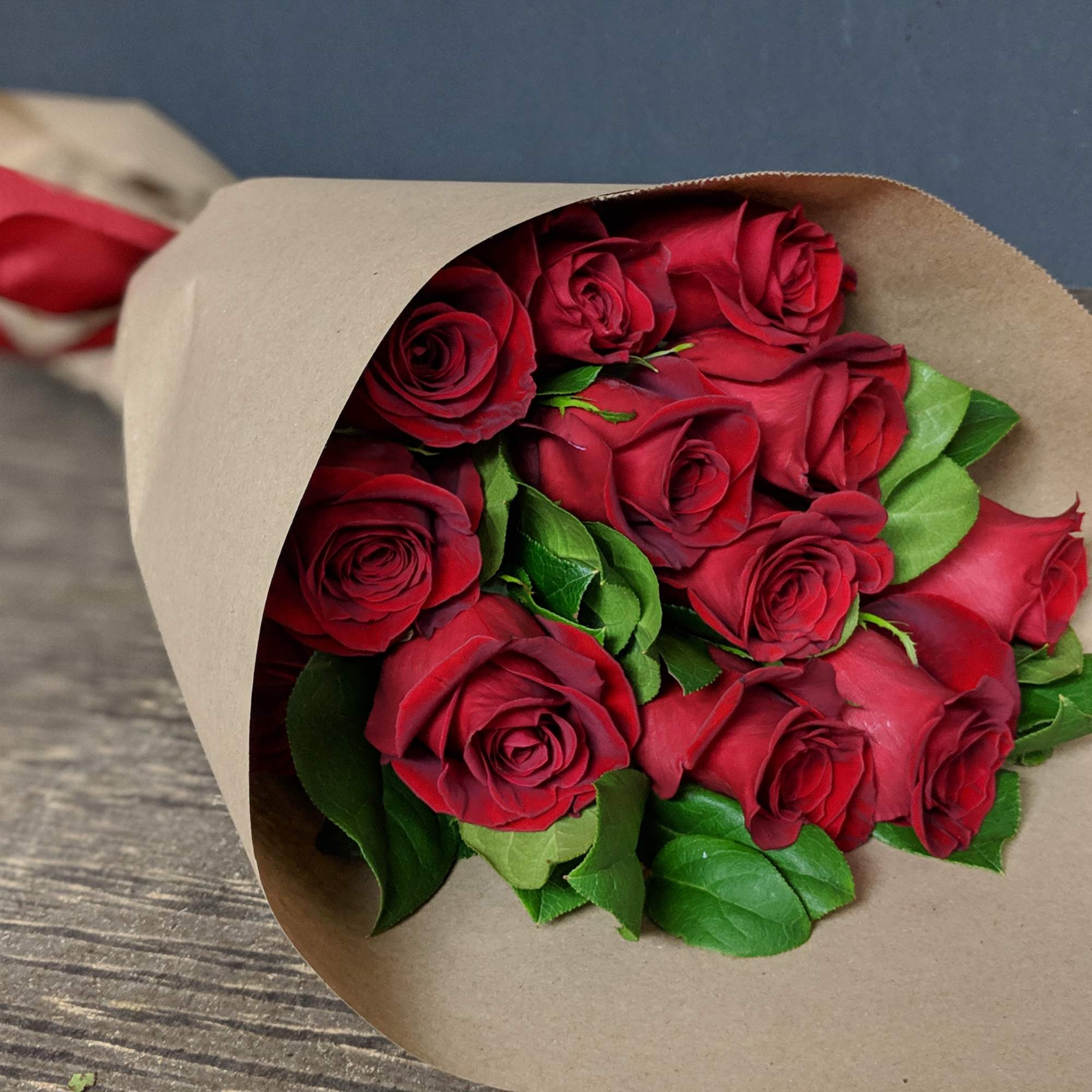One dozen long stem red roses hand wrapped in brown paper. This