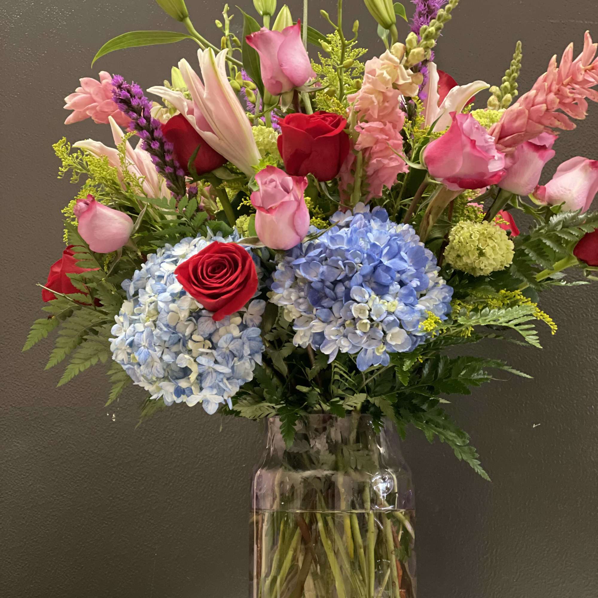 This beautiful arrangement made with blue hydrangea ,  pink ginger, starfighter