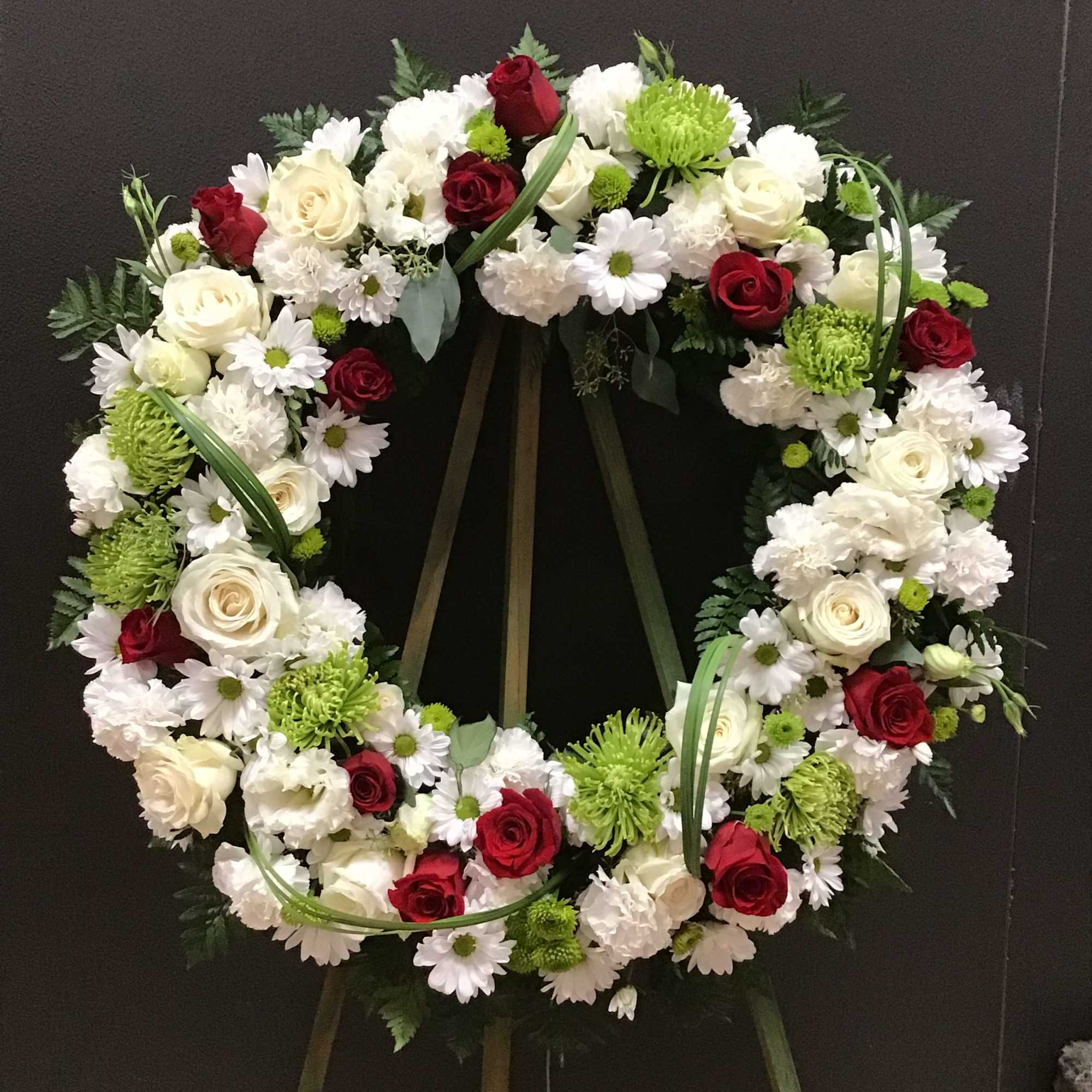 This beautiful sympathy wreath make with white, red and green color 