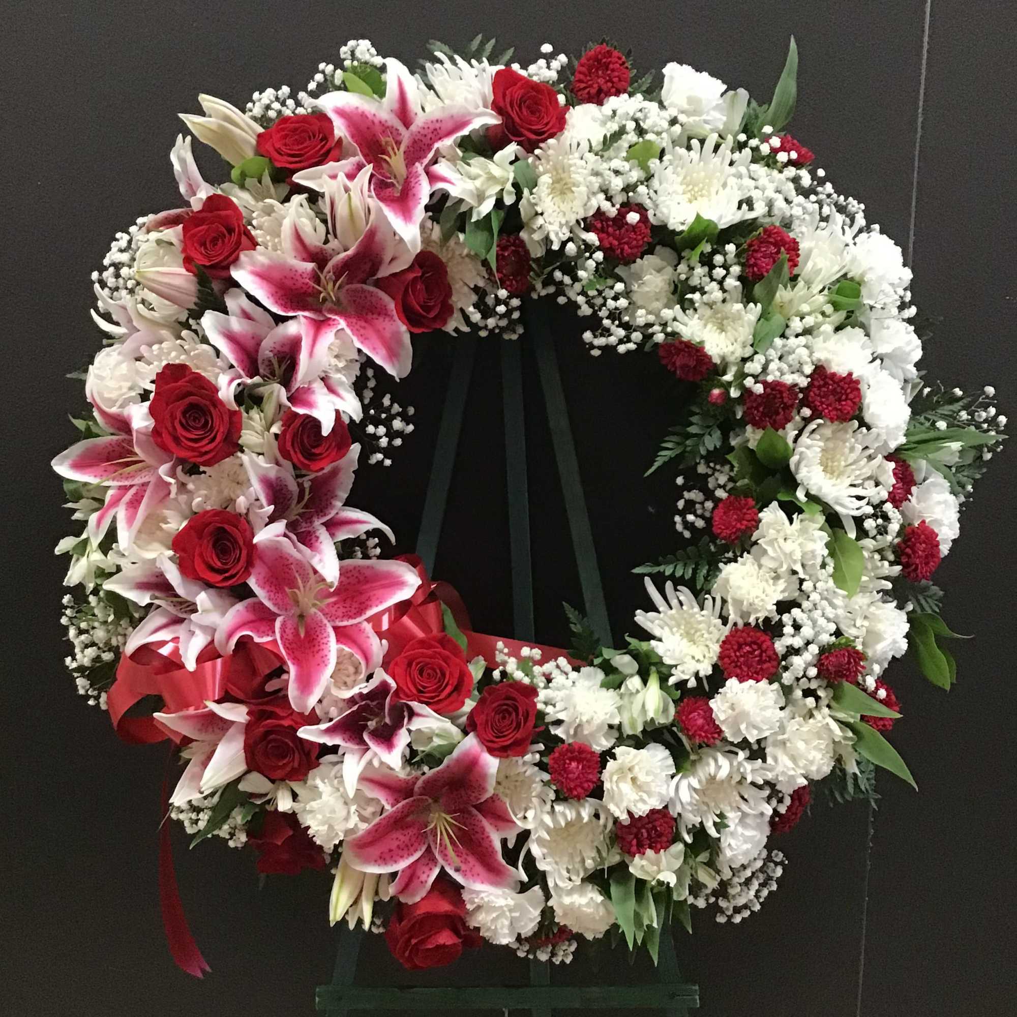 This beautiful wreath make with pink lilies , red roses, and white