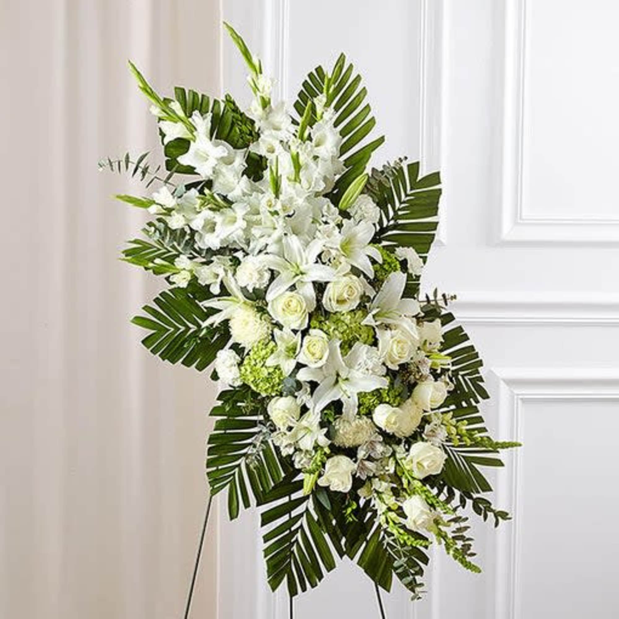 This standing spray with fresh white roses, lilies and carnations, green hydrangeas