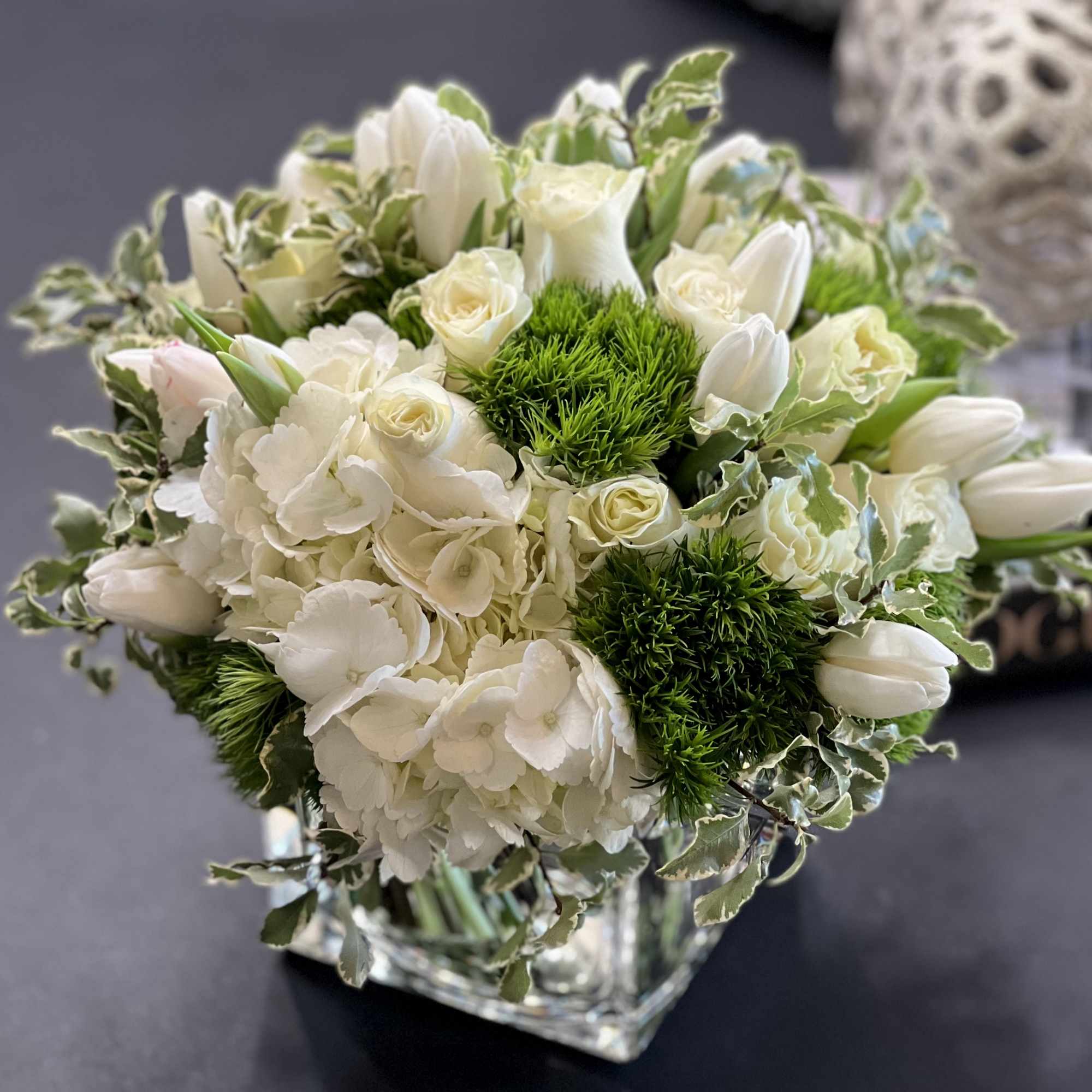 White and green flower design in a vase. 
White hydrangeas, tulips, green