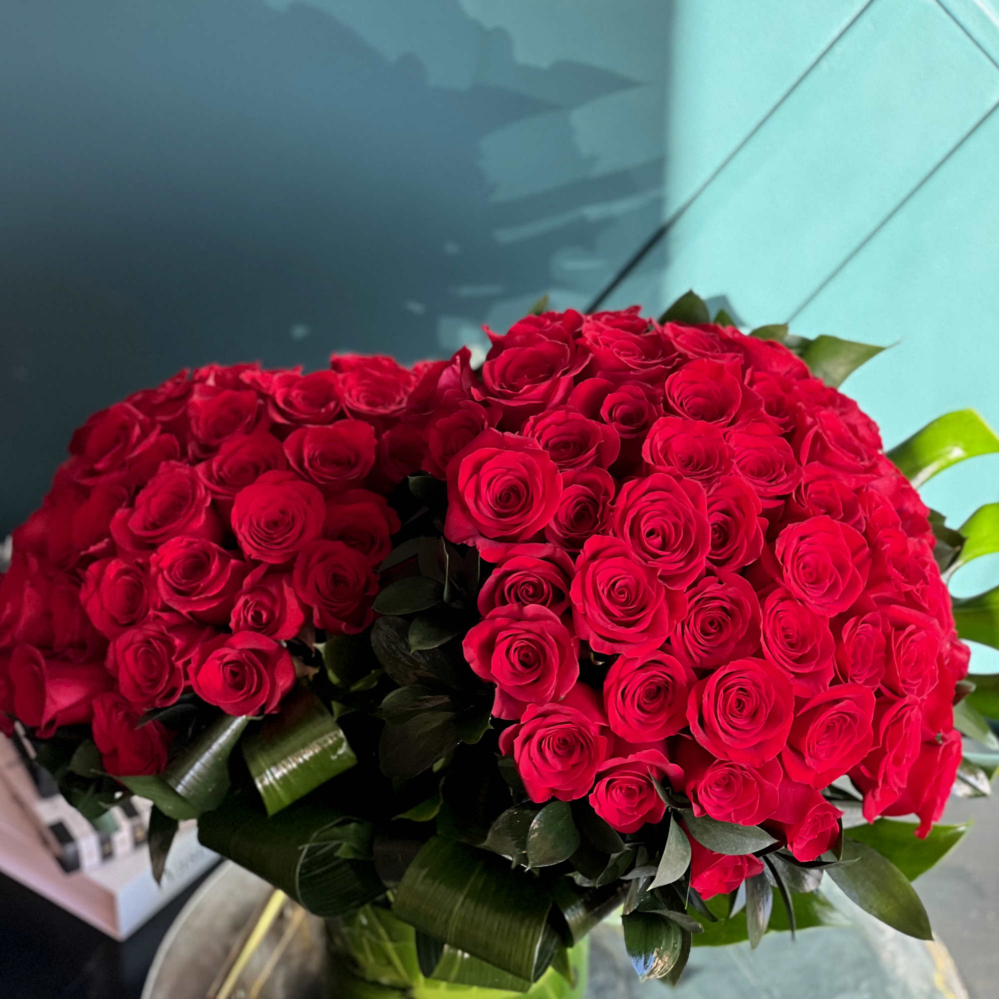 100 premium red roses in a clear vase with greenery accent 