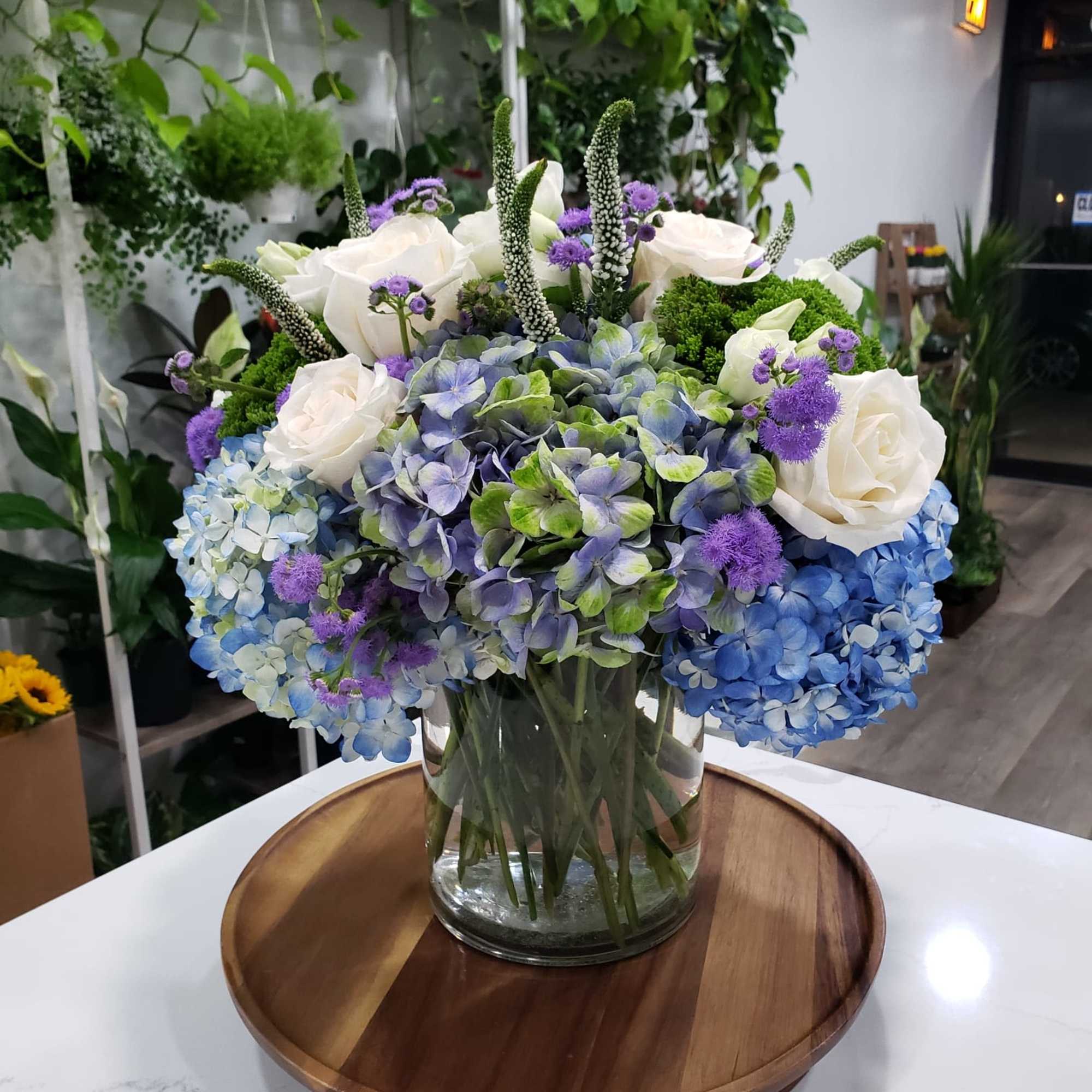 This gorgeous arrangement has blue and blue-green hydrangeas, Veronicas, roses, traceliums, floss